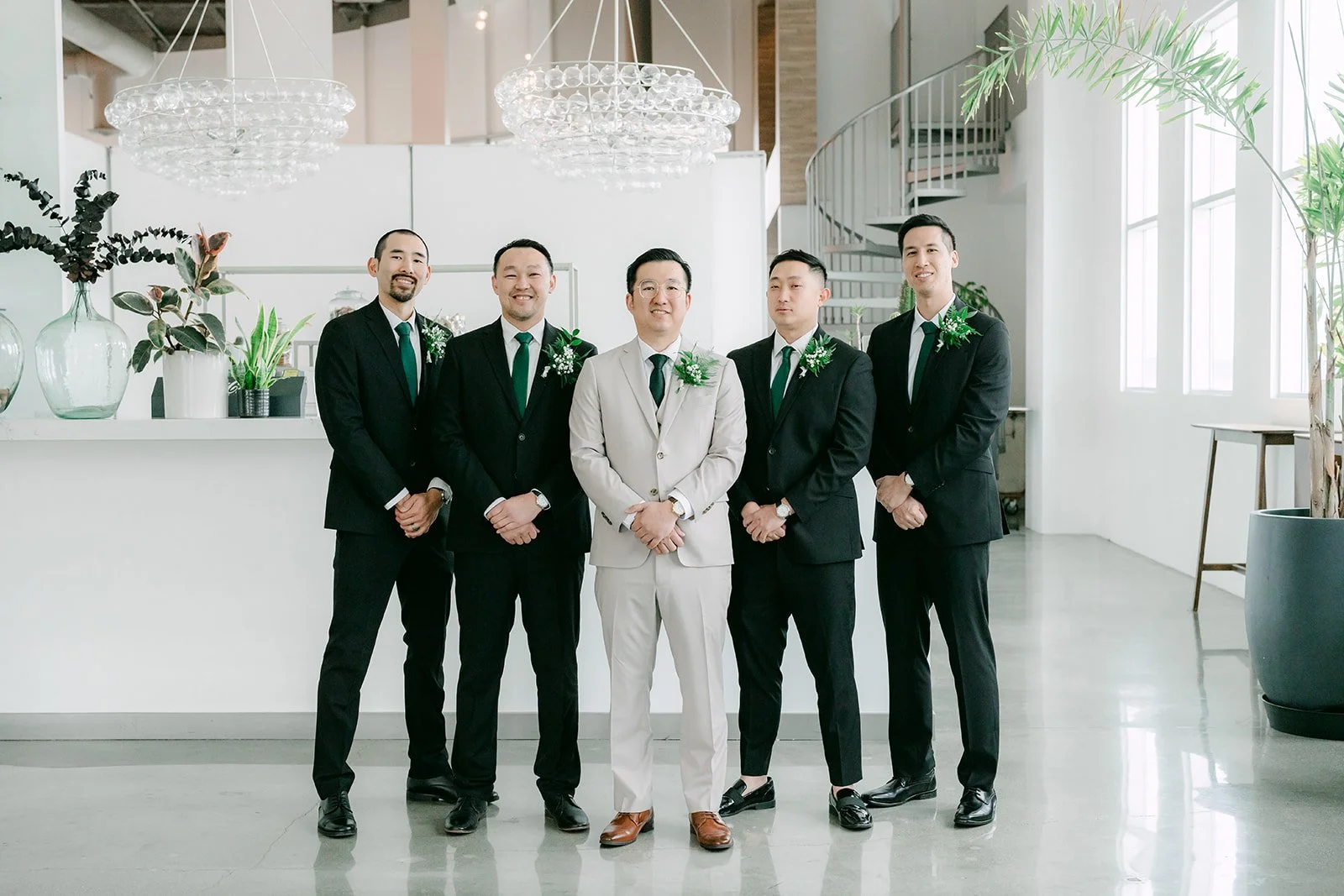 Groom and groomsmen in black suits lined up inside The Modern