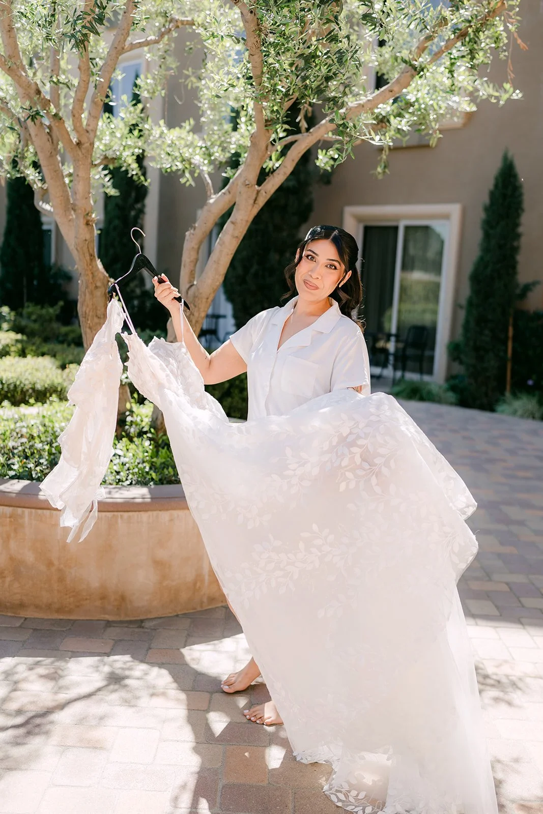 Fernanda holding up the train of her gown in the hotel courtyard.
