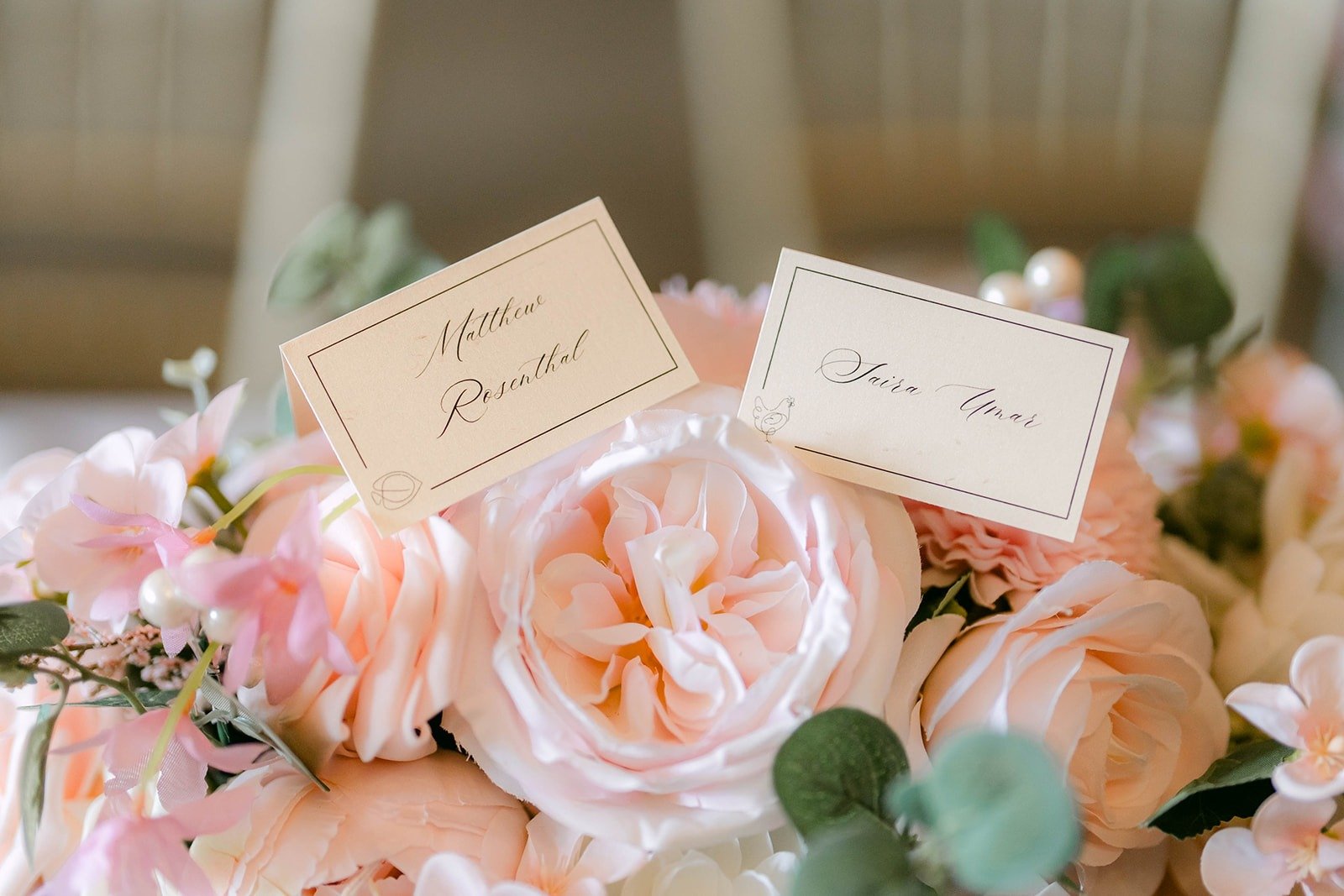 Calligraphy name cards tucked among blush roses