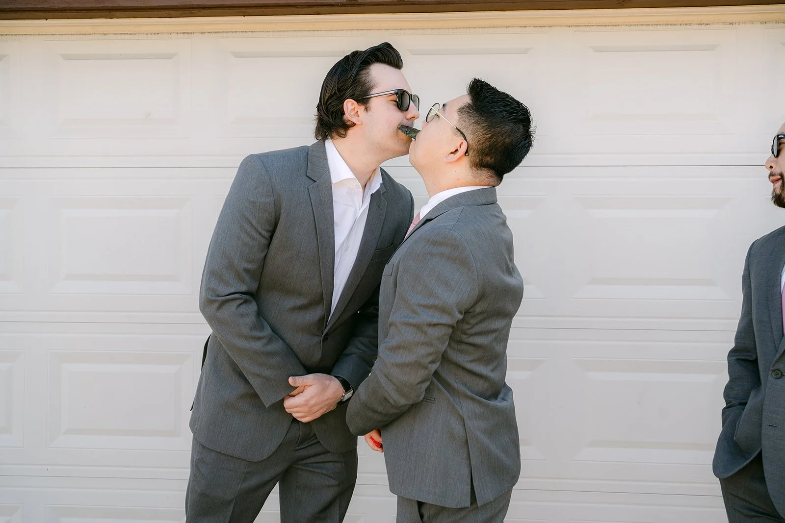 Two groomsmen joking around in front of the garage.