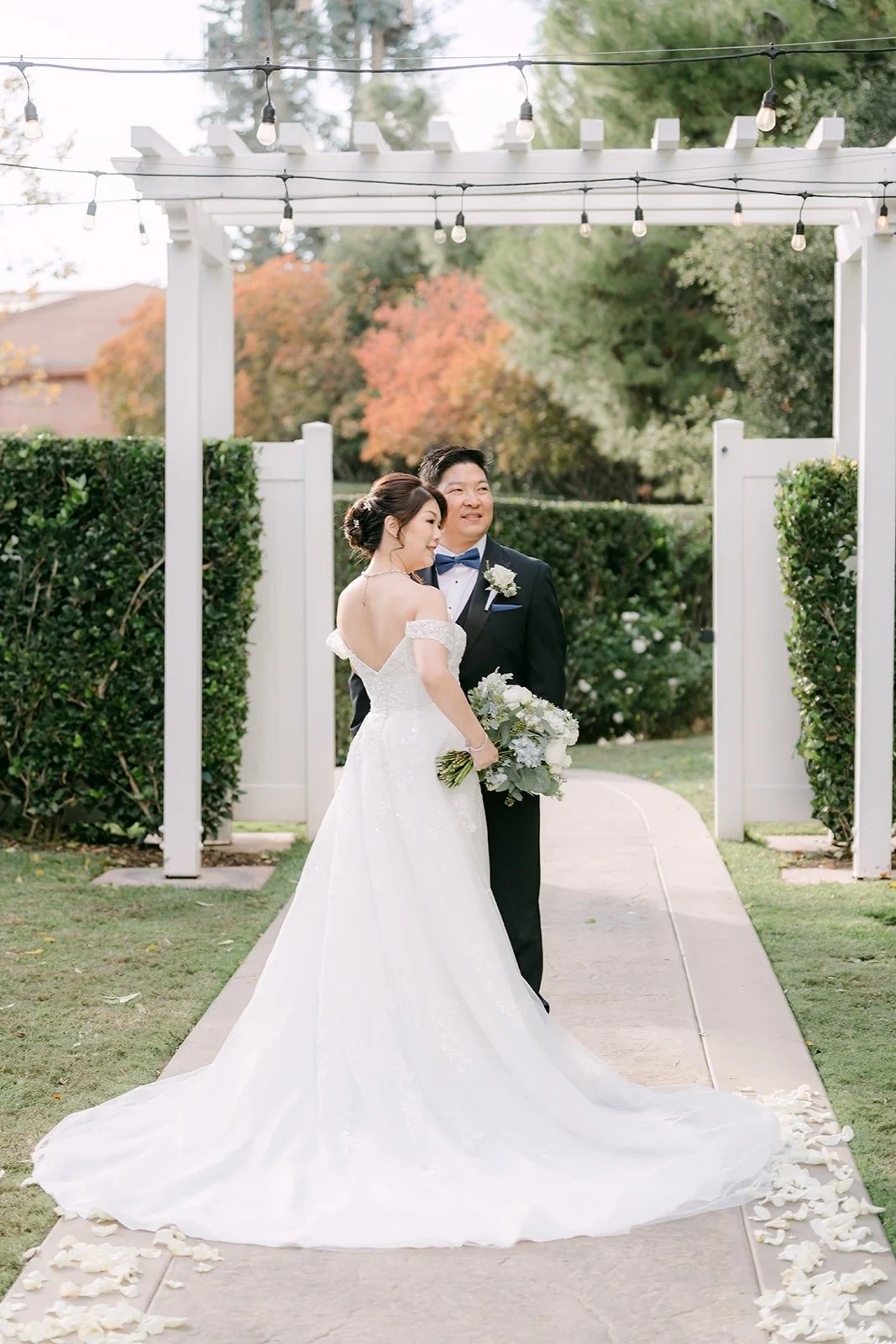 Sochi and Jay under the white arbor in the ceremony garden at Sierra La Verne