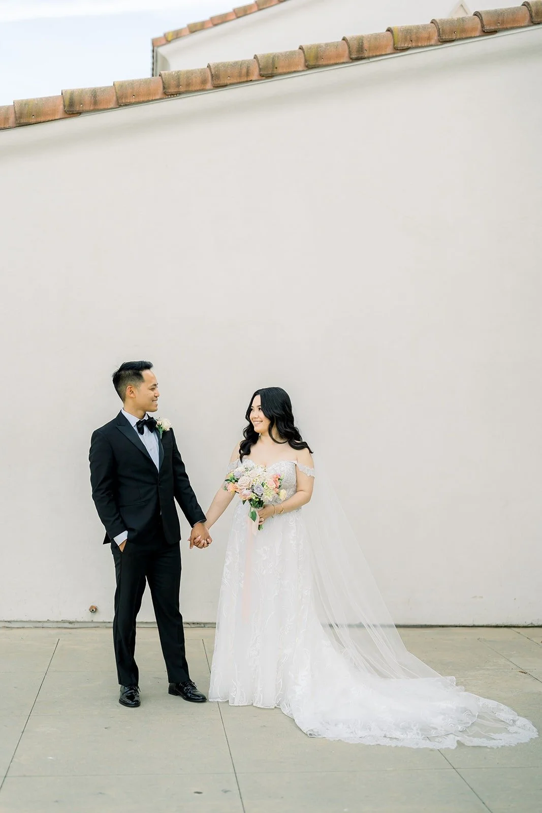Francesca and Ralph holding hands against a white stucco wall