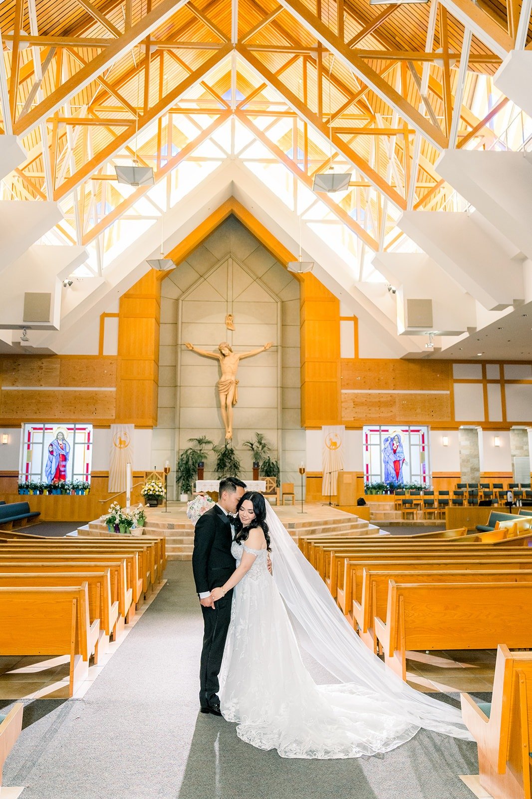 Wide portrait of Francesca and Ralph in the aisle with her cathedral veil spread behind her