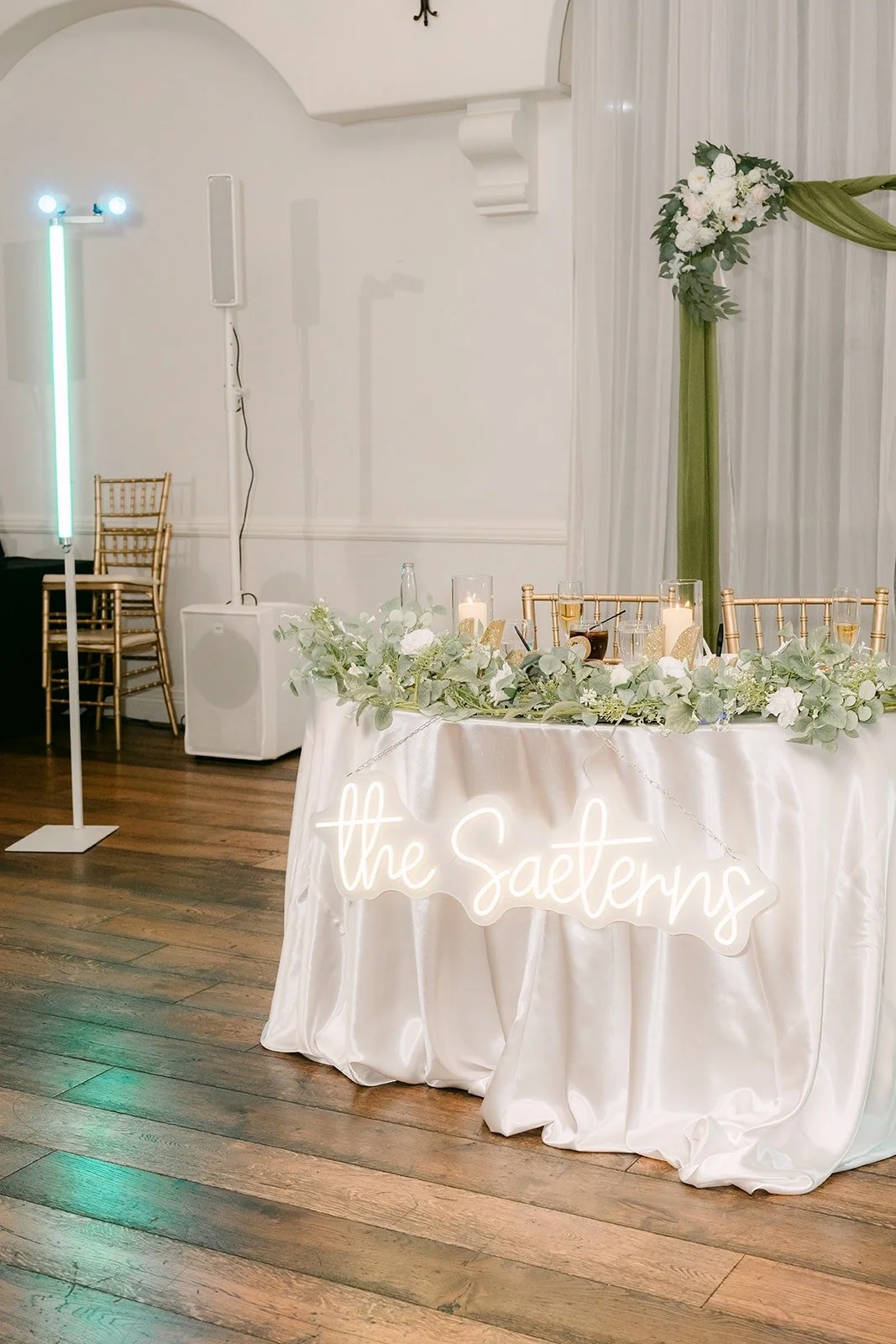 Head table draped in white with greenery