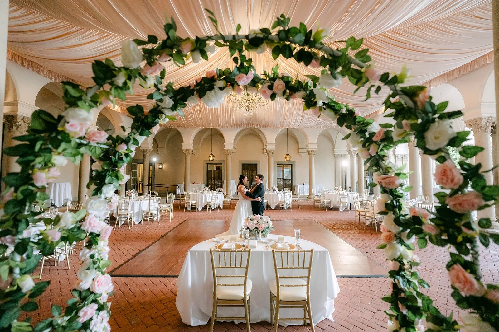A view through the rose arch of Saira and Matthew dancing alone