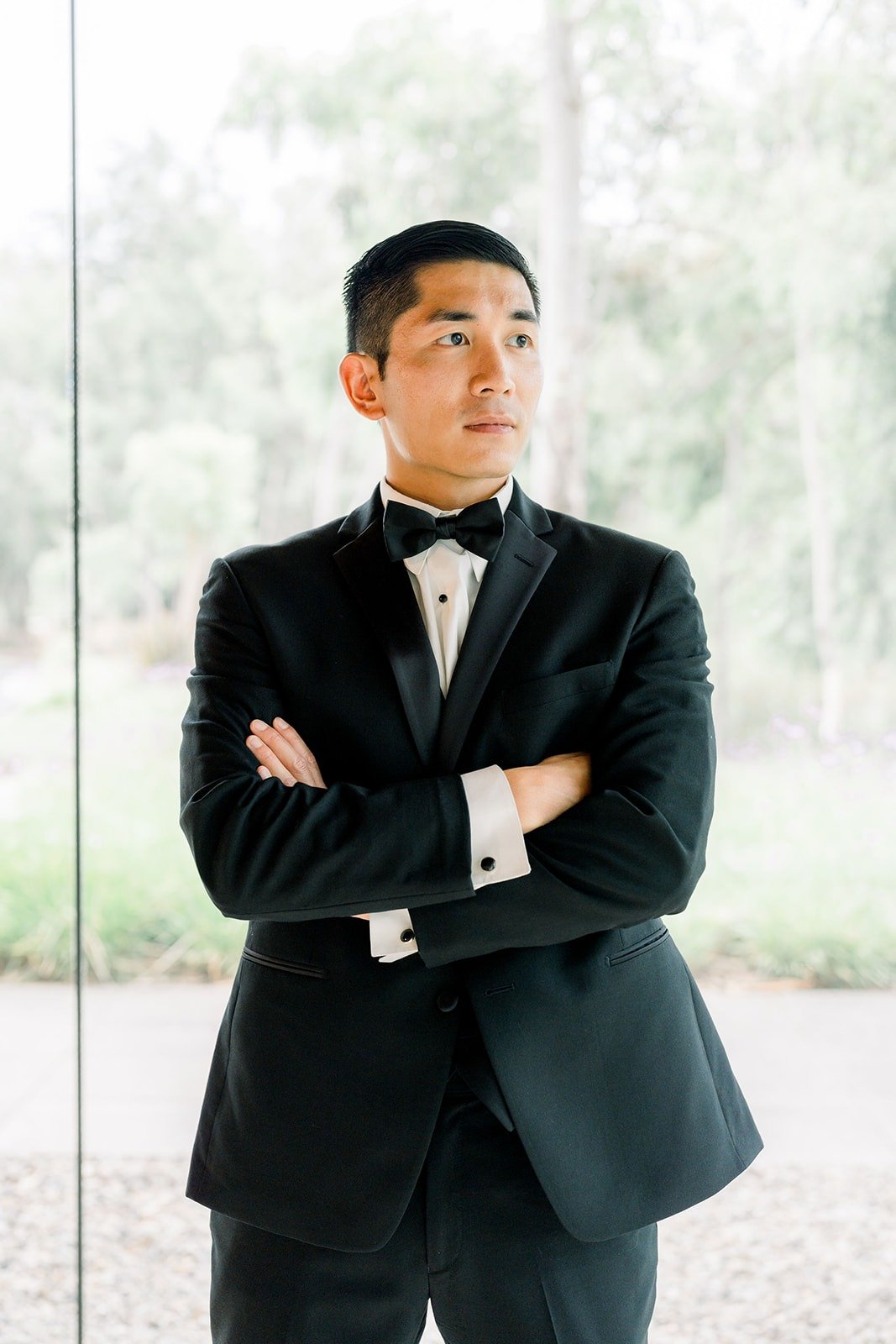 Steven stands with arms crossed beside the glass wall