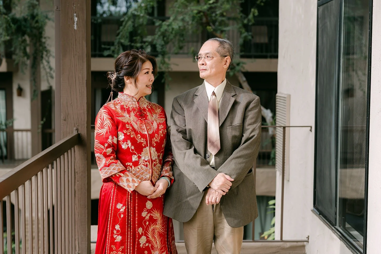 Sochi in her red and gold attire with a family member by the balcony doors
