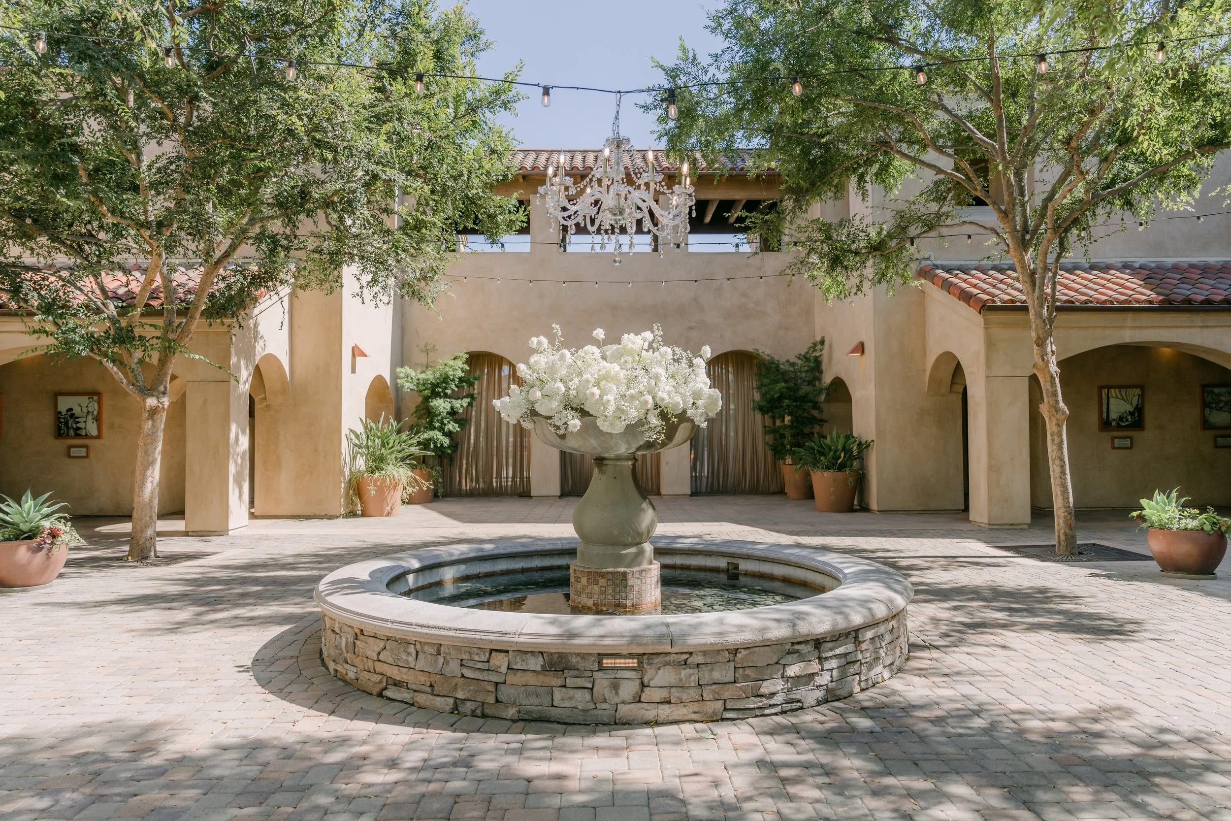 Courtyard fountain dressed with white florals at Serra Plaza in San Juan Capistrano