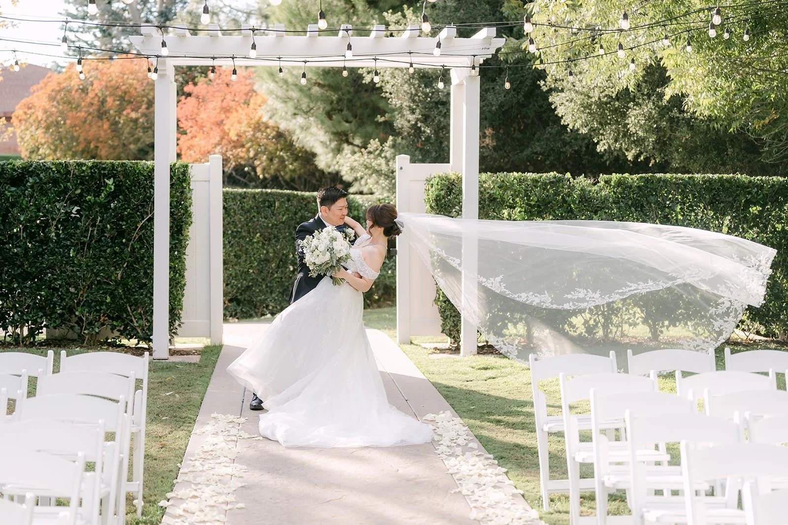 Sochi's veil floats in the breeze as Jay dips her for a kiss under the arbor