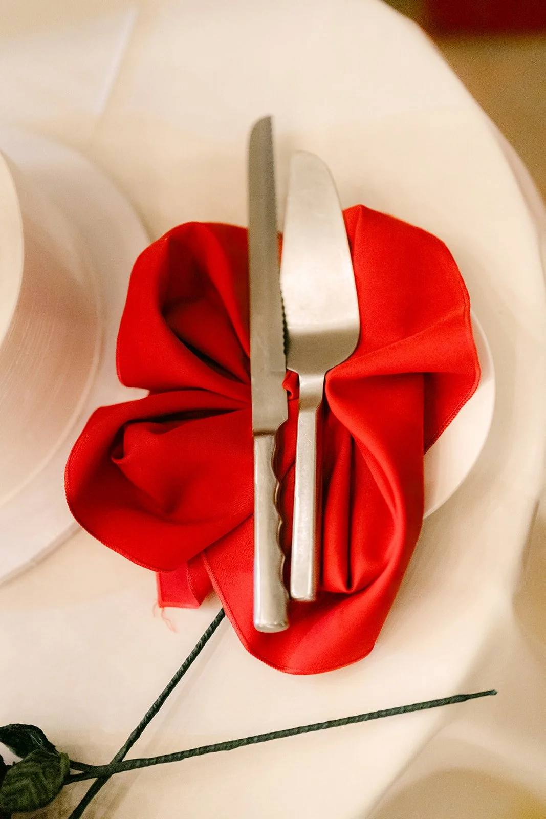 Red napkin and silverware at a place setting.