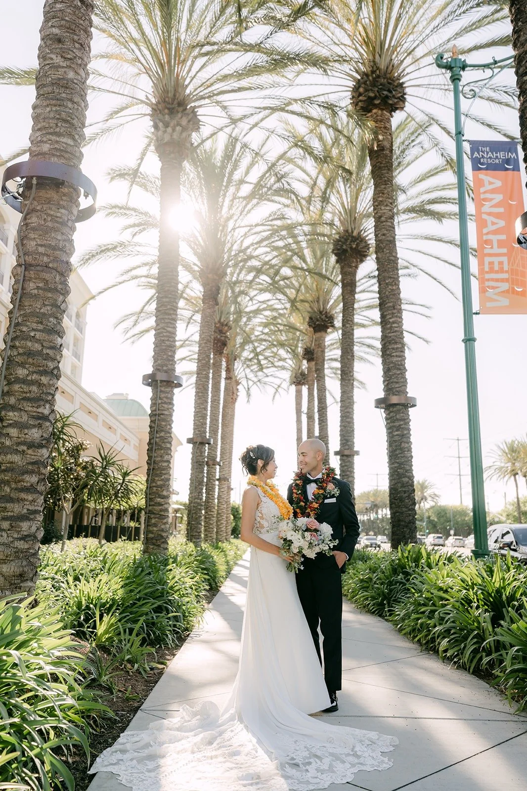 Francesca and Daniel walk between the tall palm trees outside the Westin