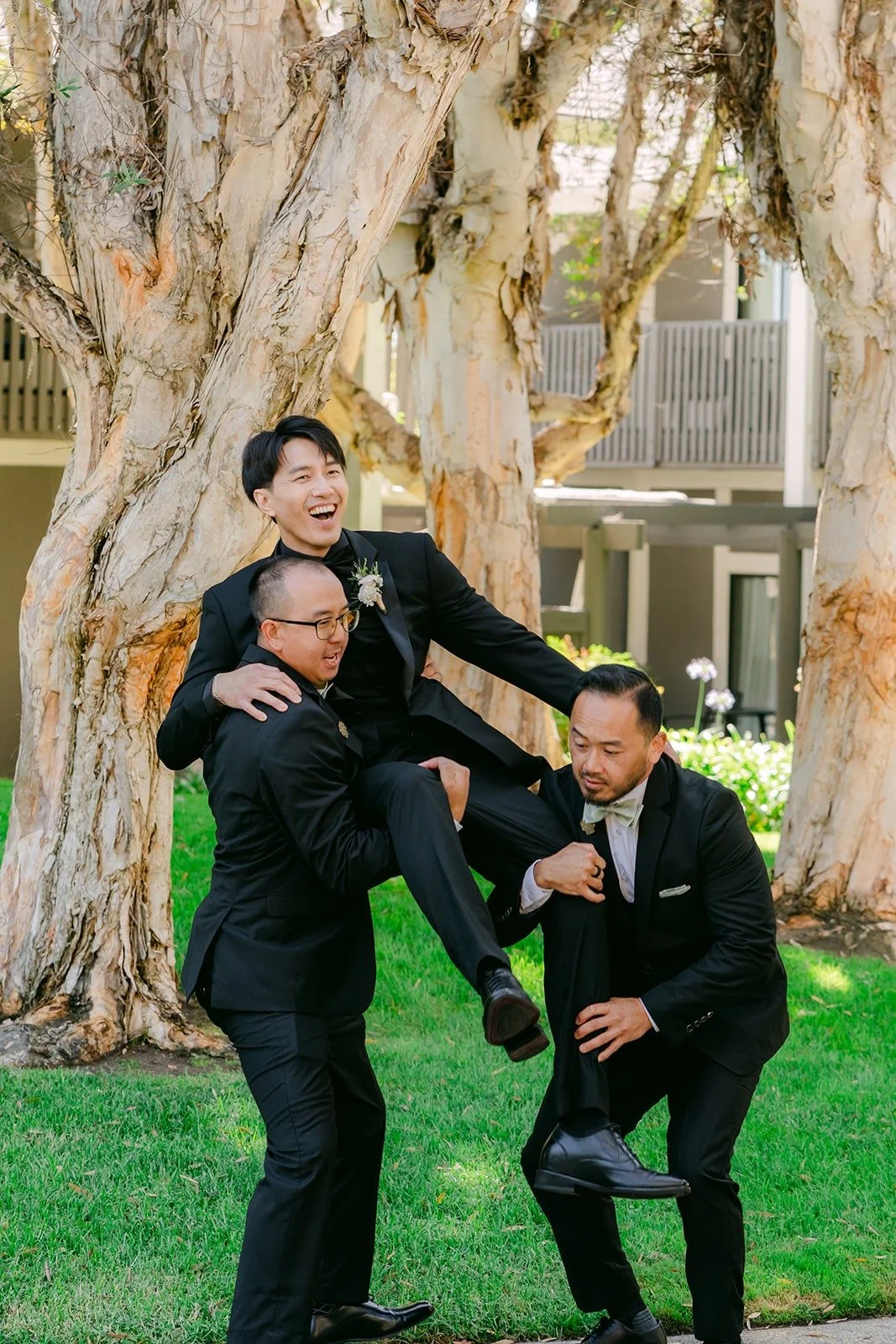 Fong's groomsmen lifting him up on the lawn, photographed by One and Only Production