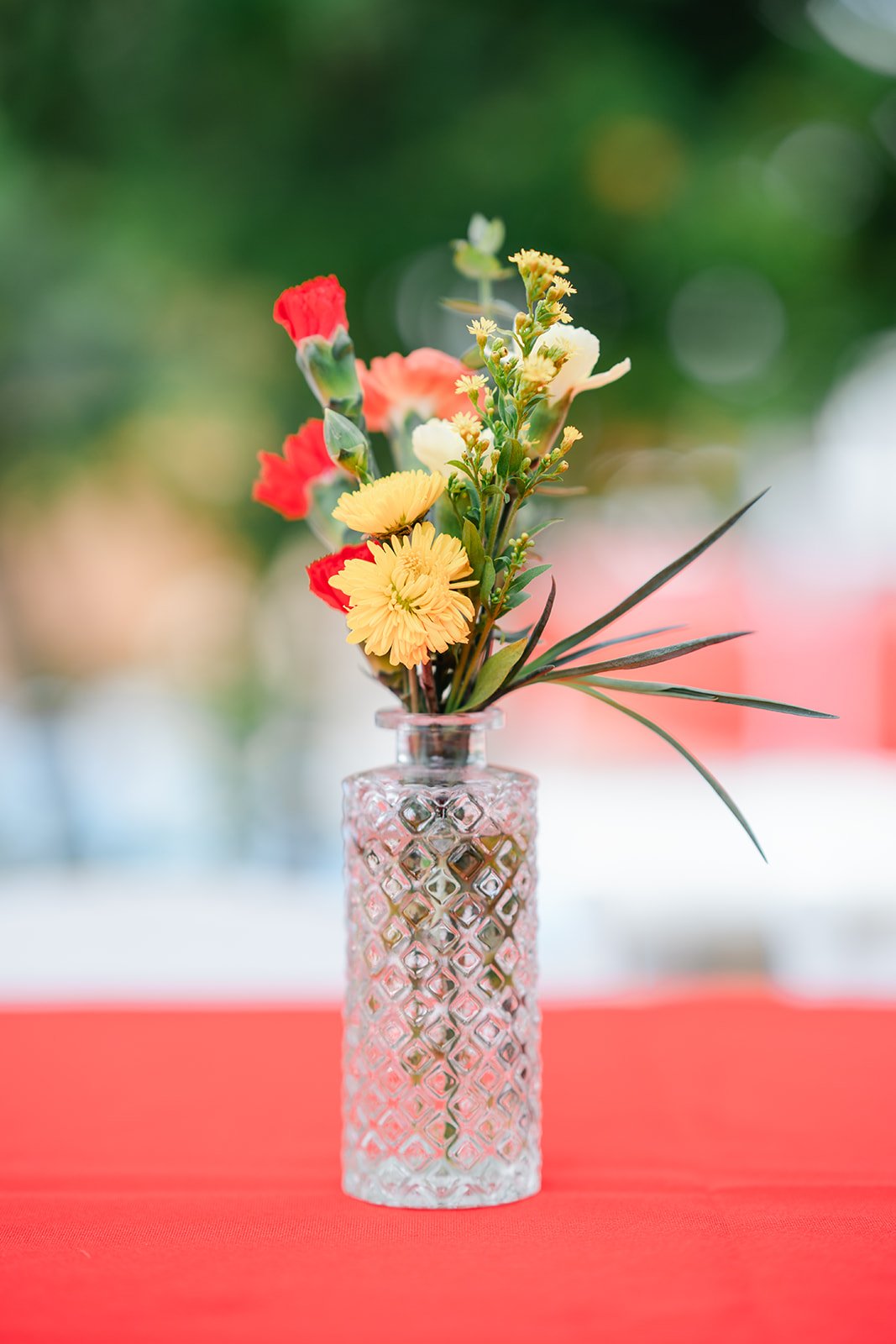 A small arrangement of flowers in a glass vase on the red table.