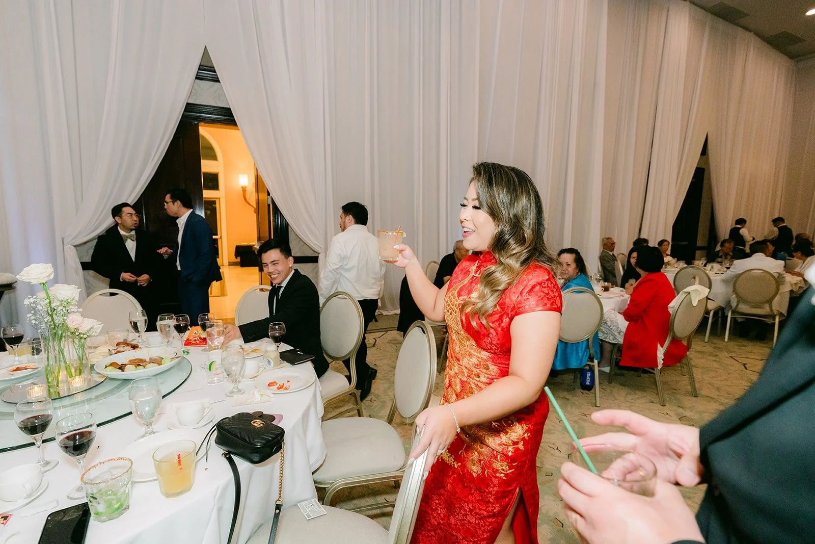 Candice in her red qipao greeting guests during table visits