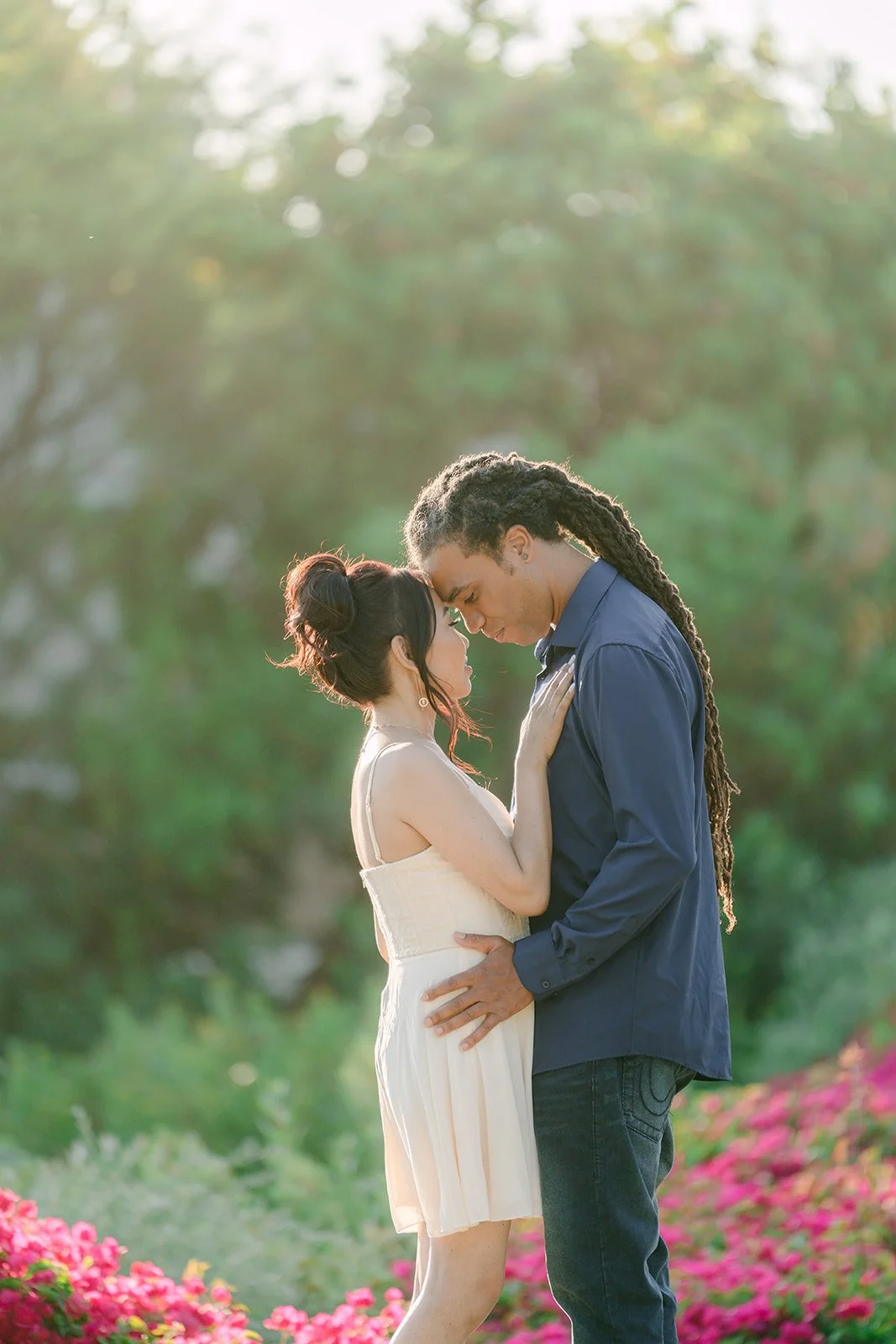 Amy and Michael touching foreheads among the bougainvillea.