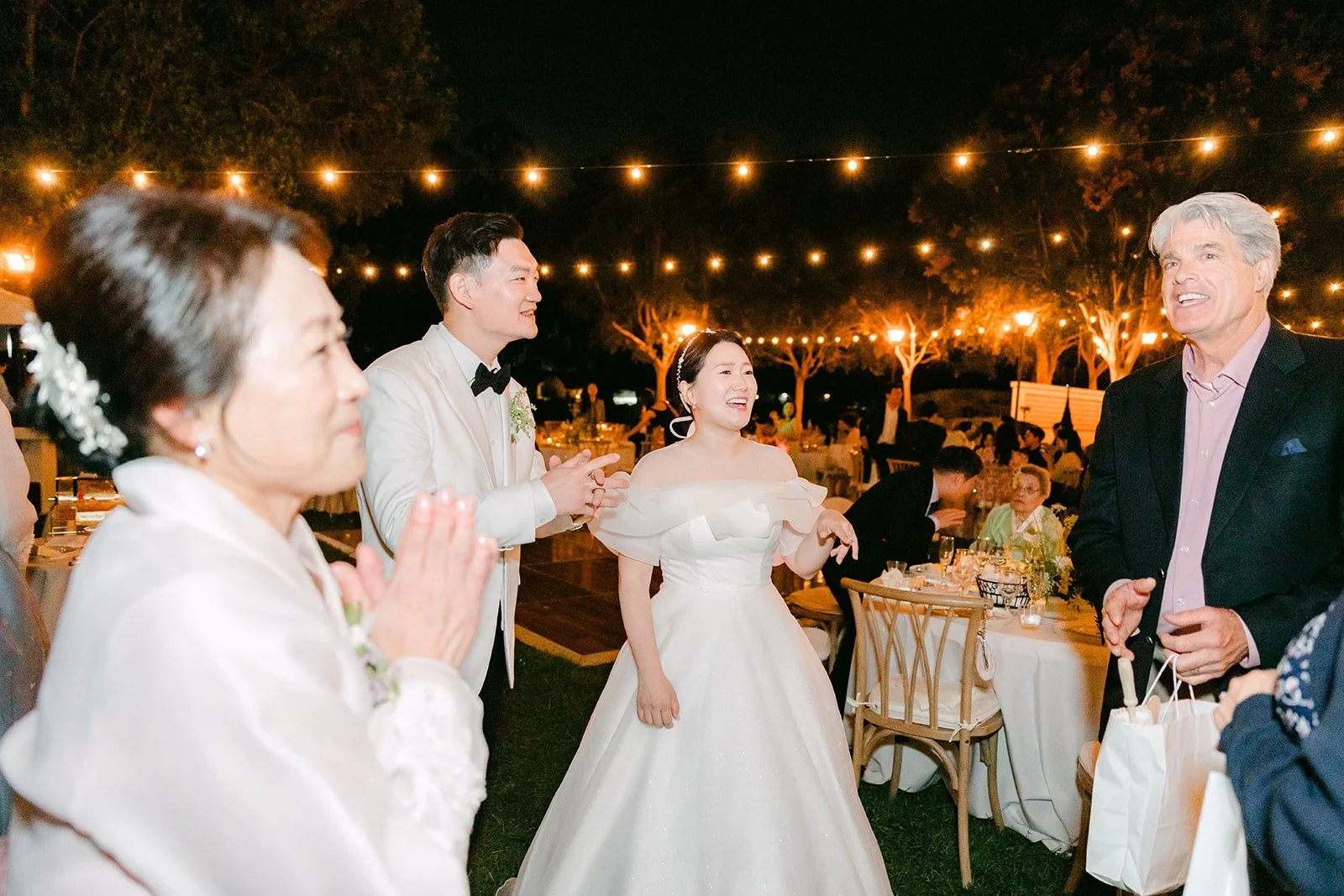 Amy and Sam with friends under the string lights, photographed by One and Only Production