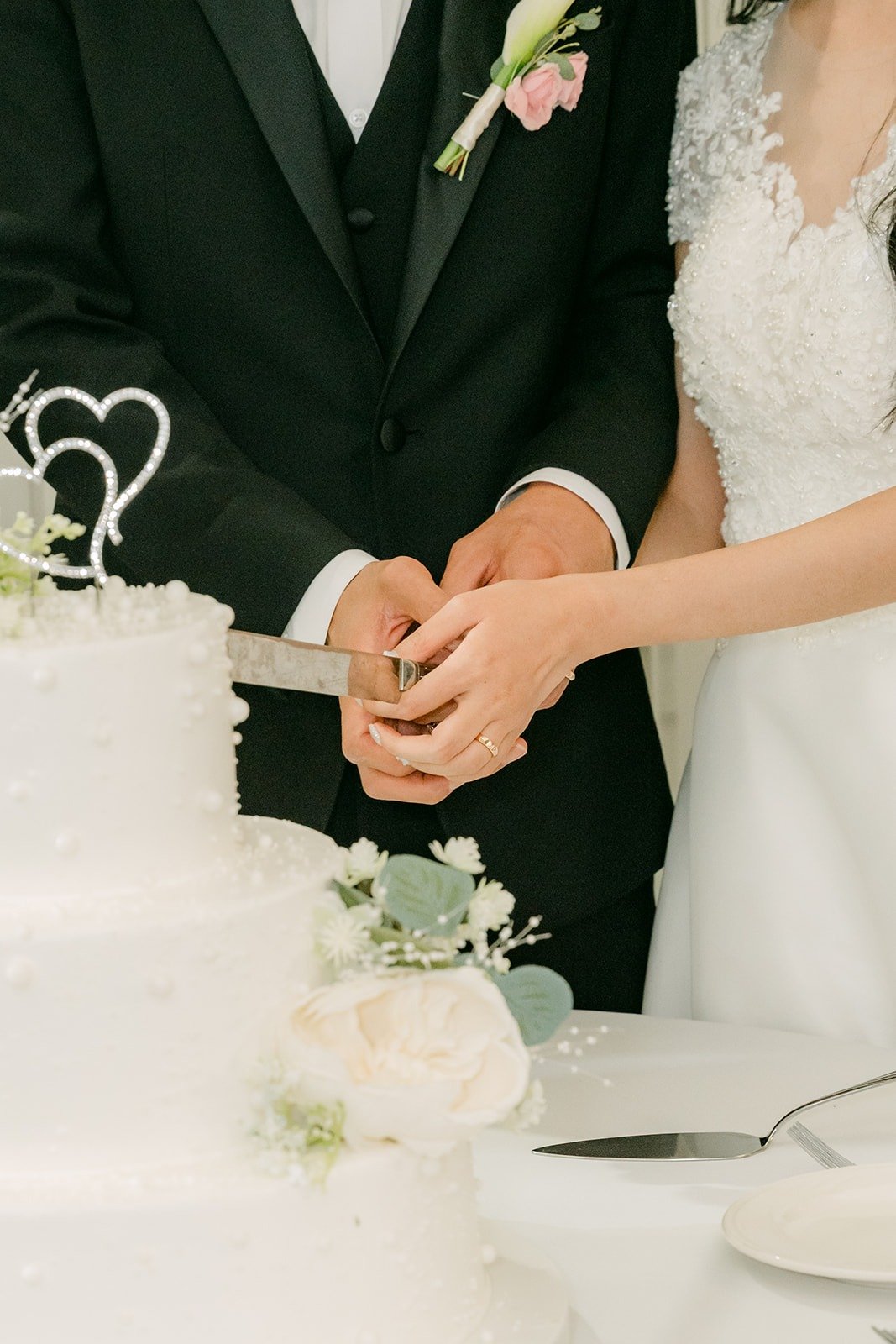 Close up of Jeannie and Eunsang's hands on the cake knife