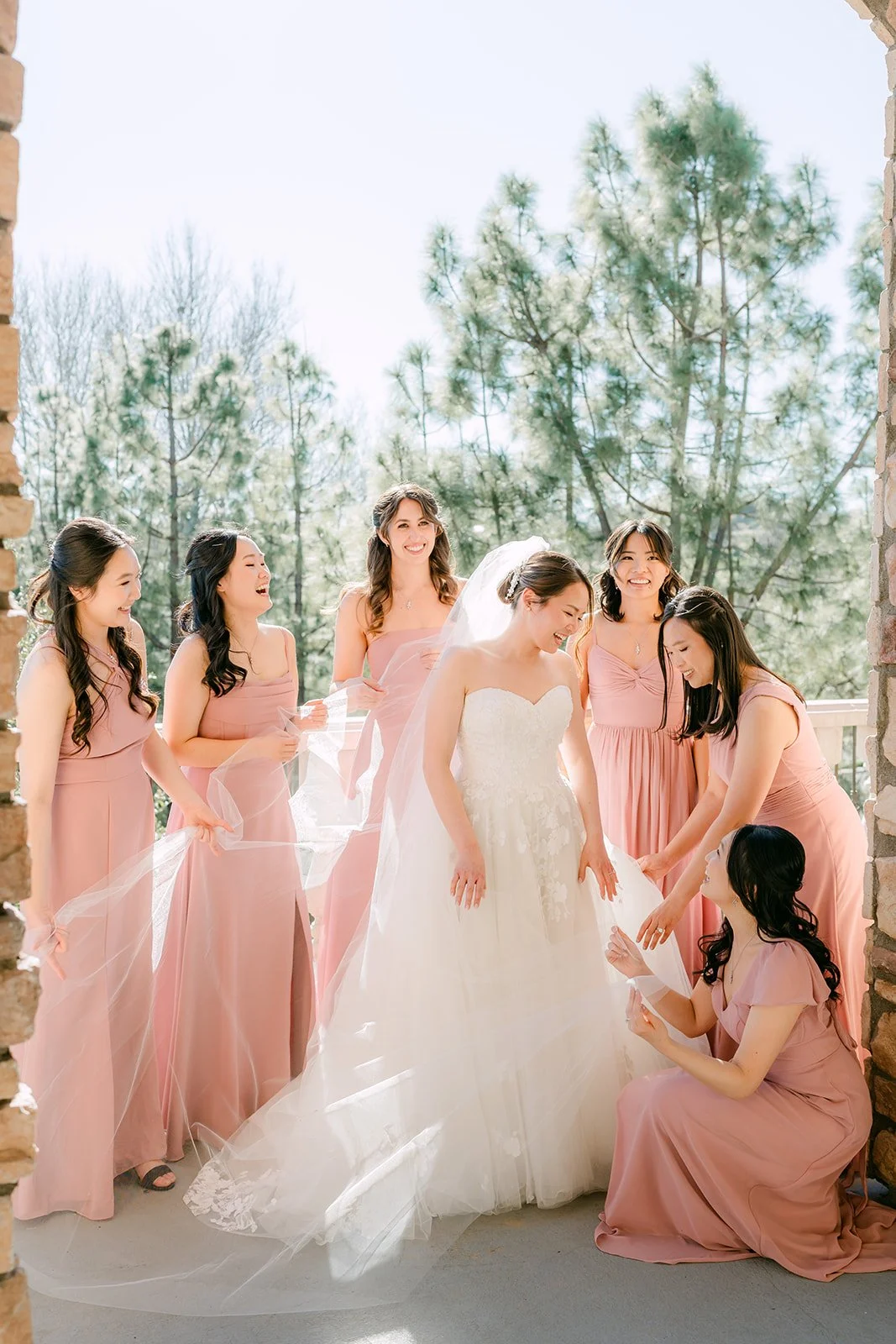 Bridesmaids helping the bride with her veil on the balcony