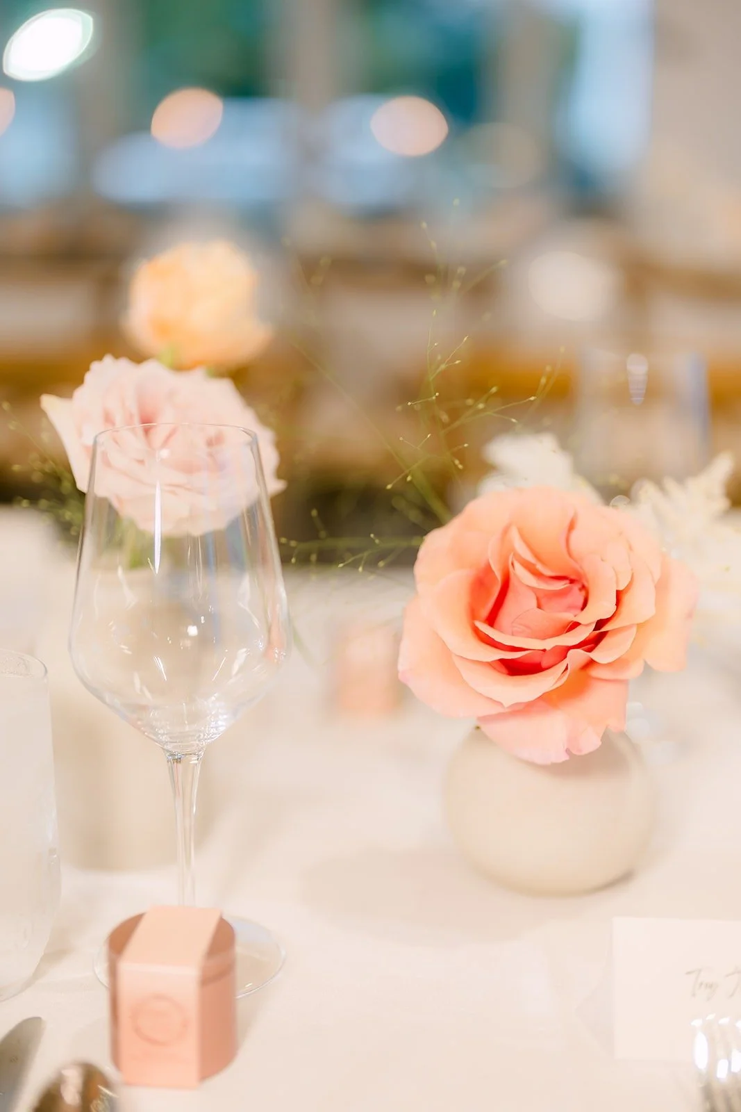 A single peach rose in a bud vase beside a place setting, photographed by One and Only Production