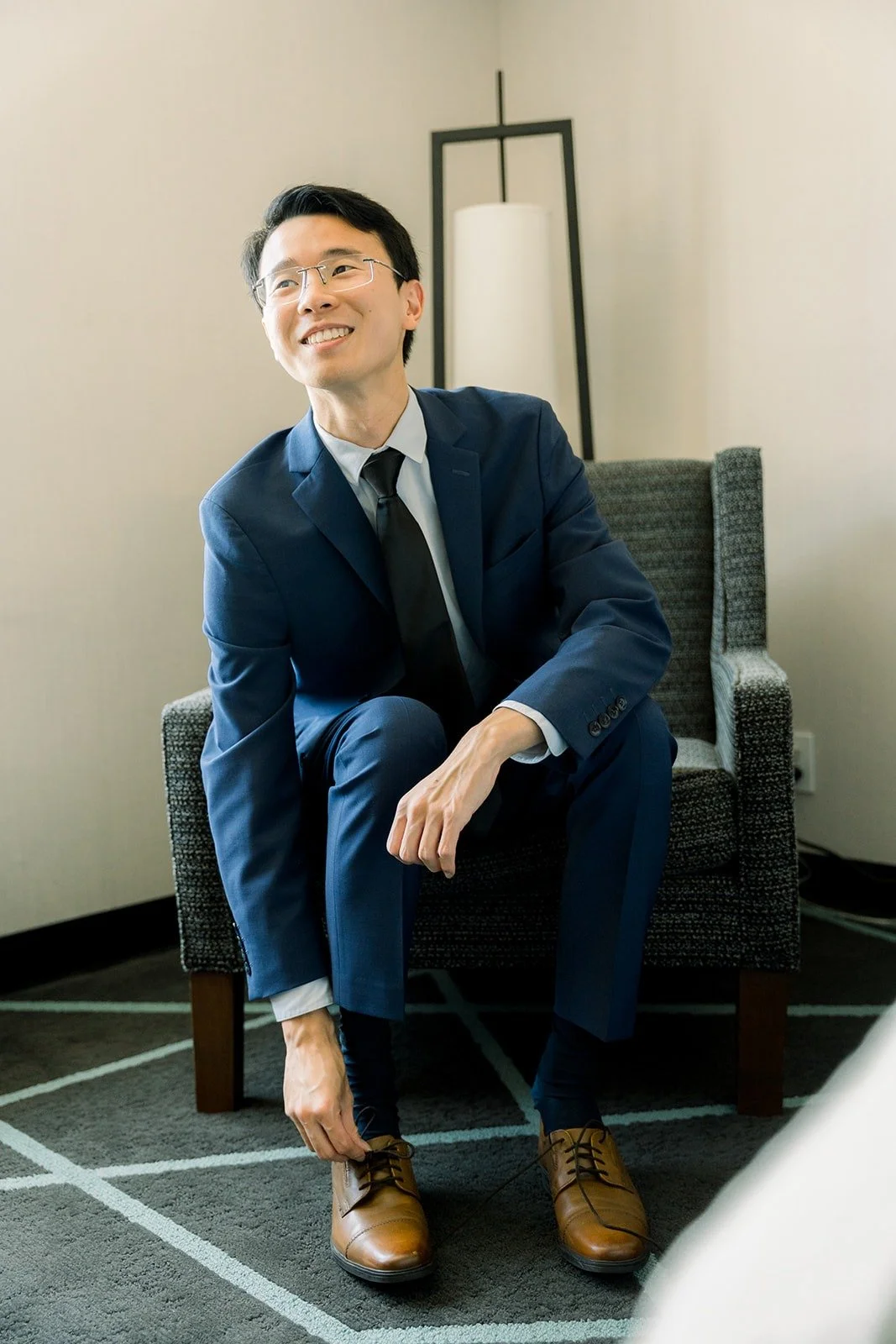 Alex sitting in the groom's room in his navy suit
