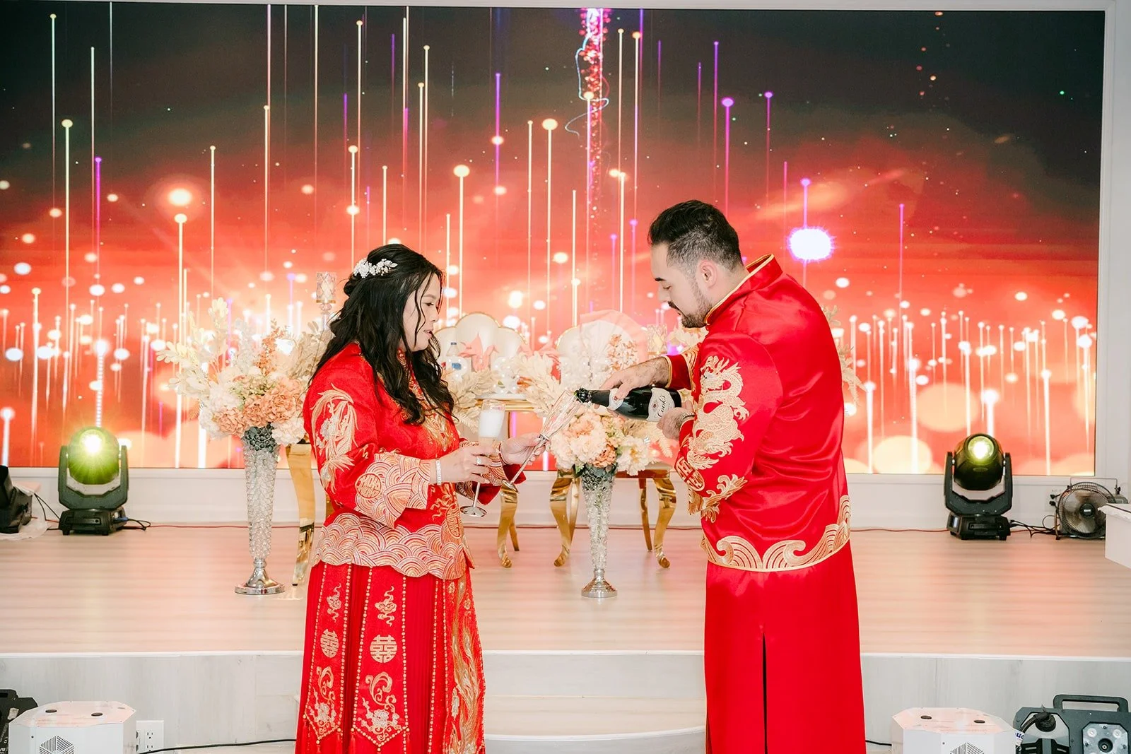 Amy and James in red in front of the glowing reception screen
