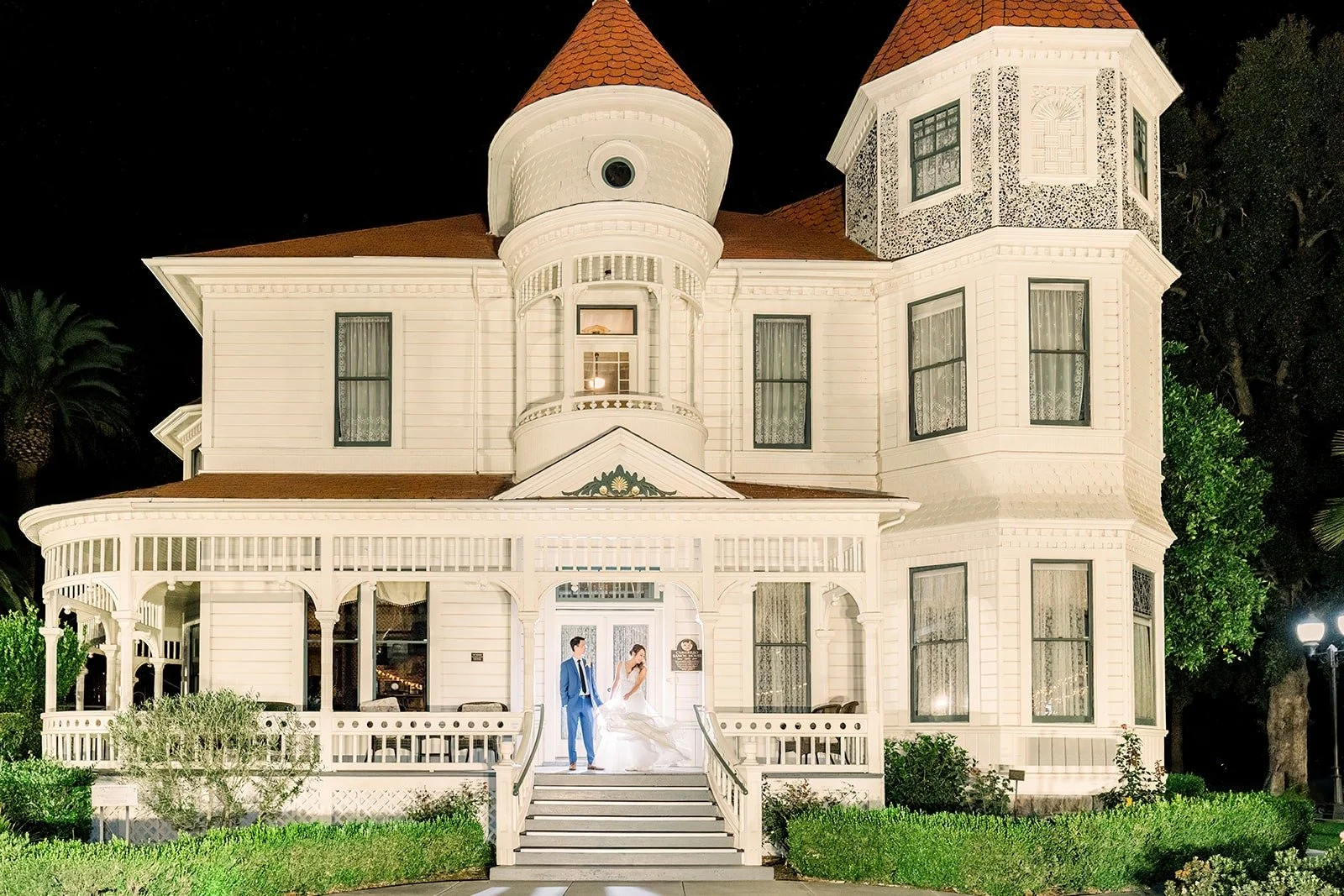 Camarillo Ranch House lit up at night with Ariel and Alex on the steps, photographed by One and Only Production