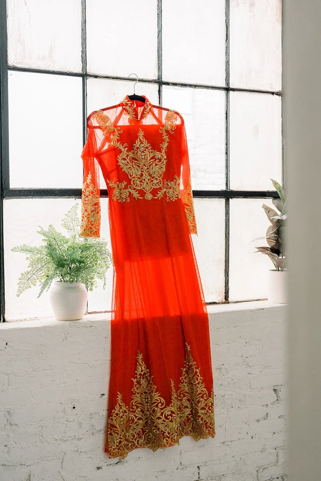 Cindy's red and gold embroidered tea ceremony dress hanging by the window