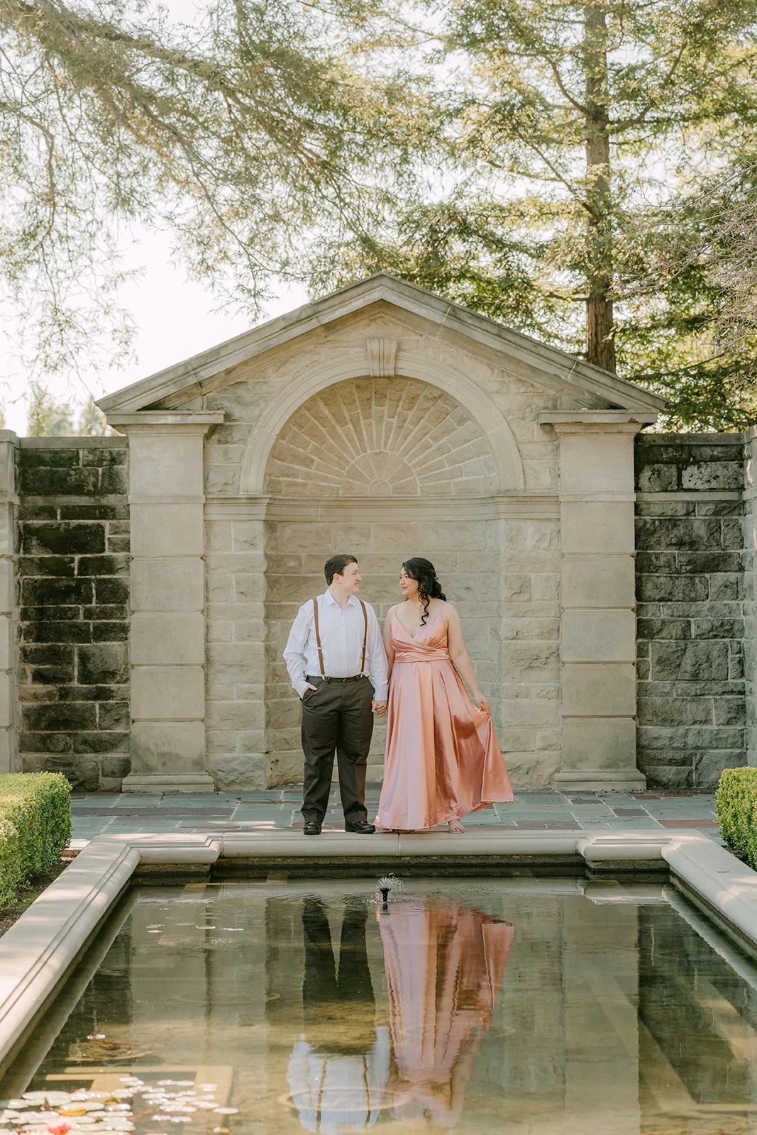 The couple reflected in the pool in front of the stone pavilion.