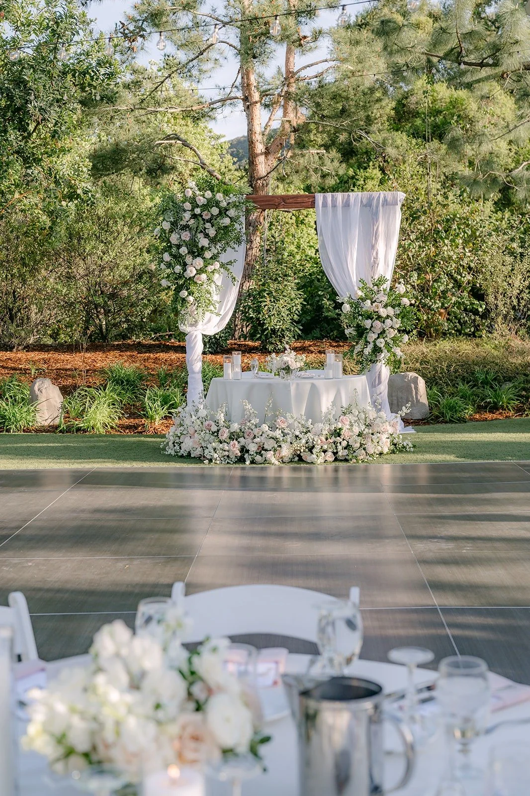 The sweetheart table under the floral arch, moved over from the ceremony, at Los Robles Greens