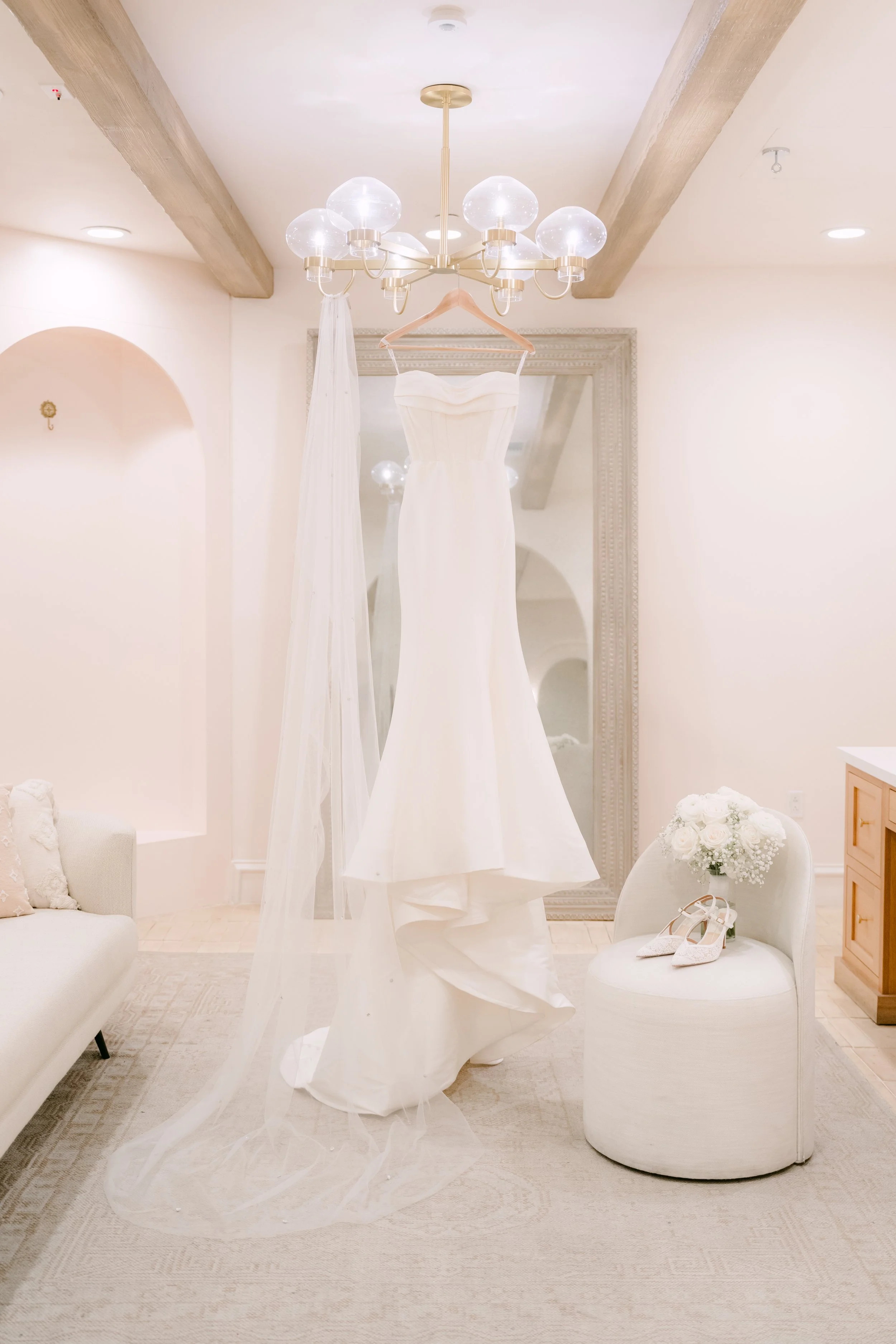 Wedding gown hanging under a globe chandelier in the Serra Plaza bridal suite