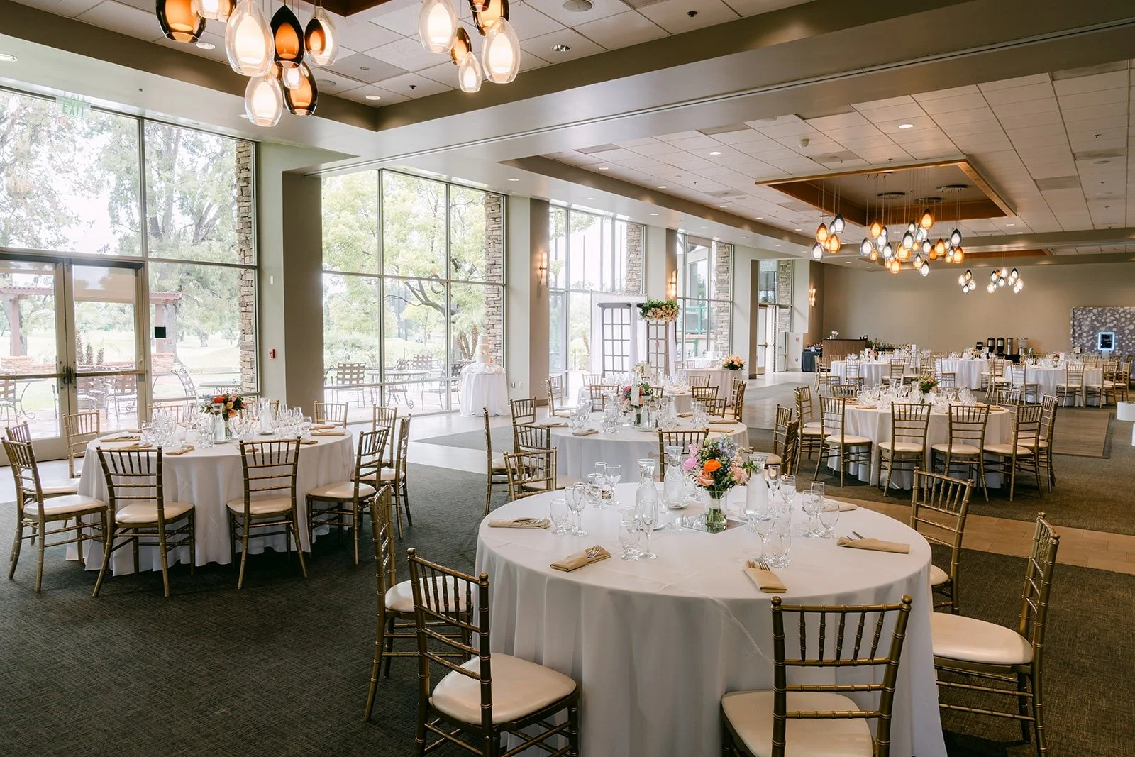 The ballroom at Rio Hondo set with round tables, gold chairs and white linens