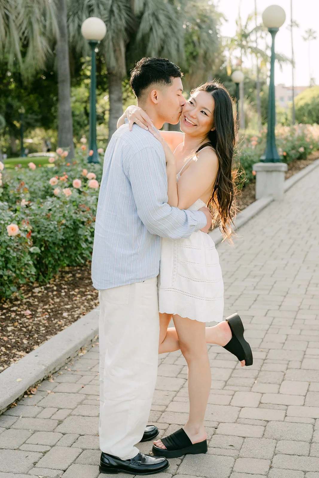 Richard kisses Jadee on the garden path as she lifts one foot.