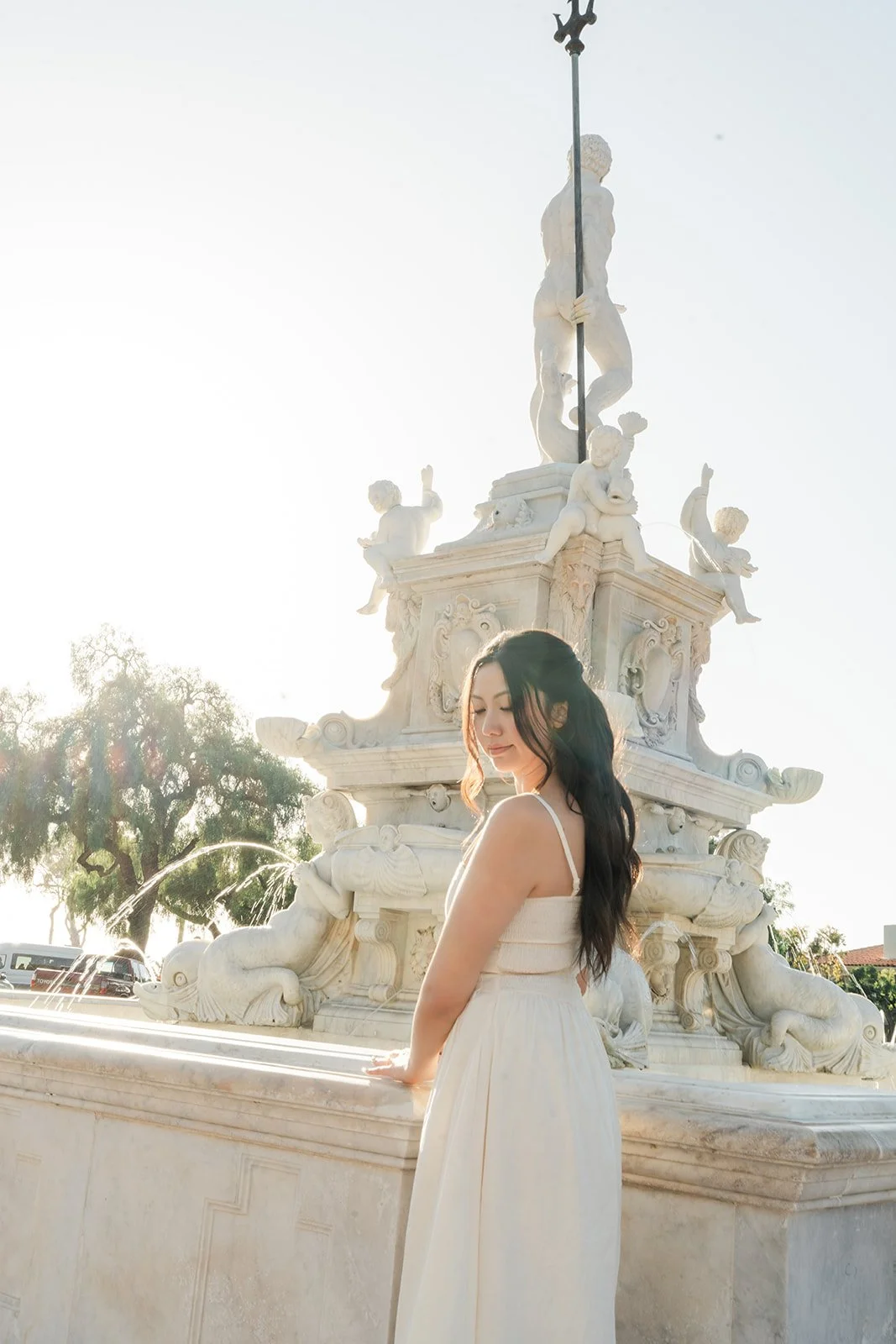 Victoria looks back over her shoulder beside the fountain.