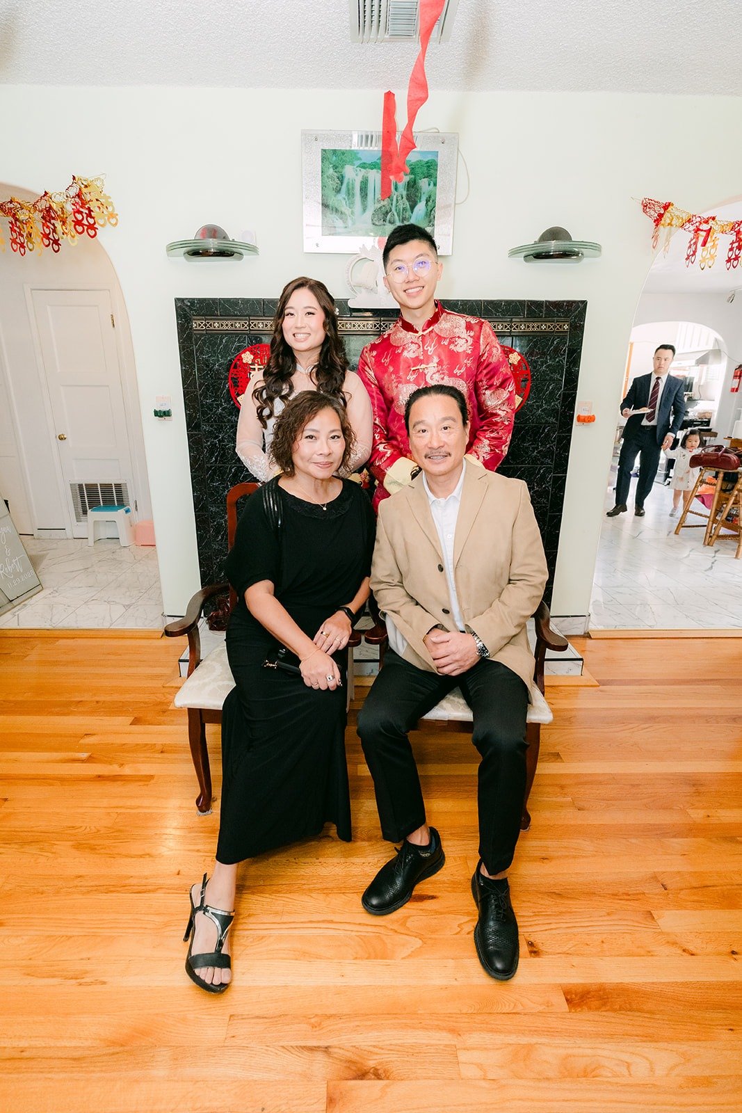 Shayna and Robert with family members seated in front of the double happiness backdrop