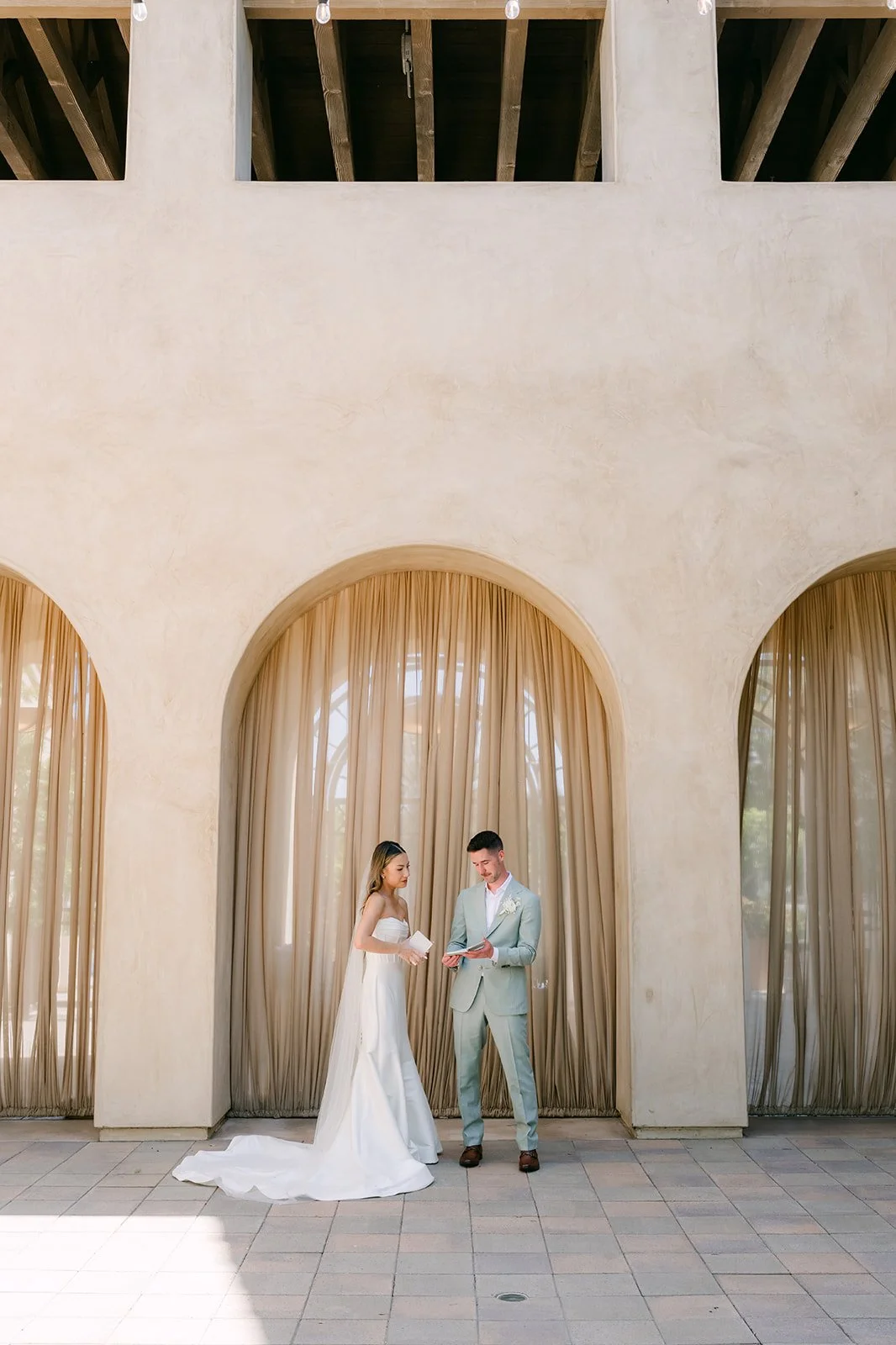 Bride and groom standing together under the tall loggia arches