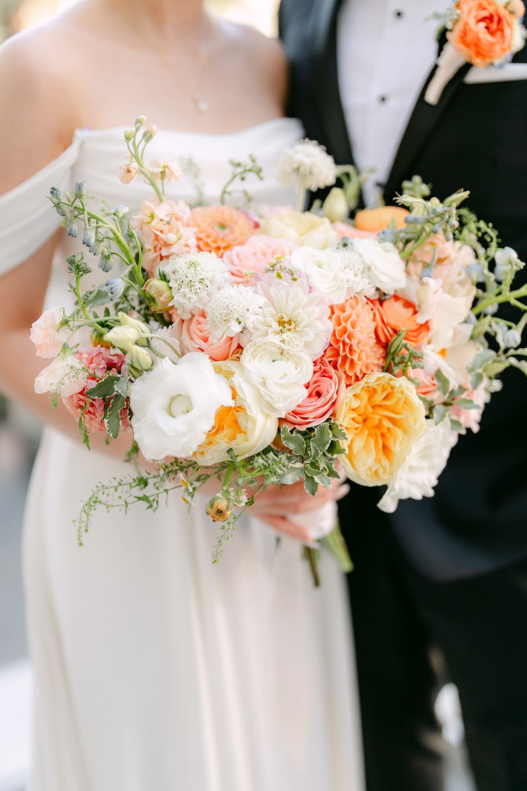 Close detail of Amanda's bouquet with San's hand at her waist.