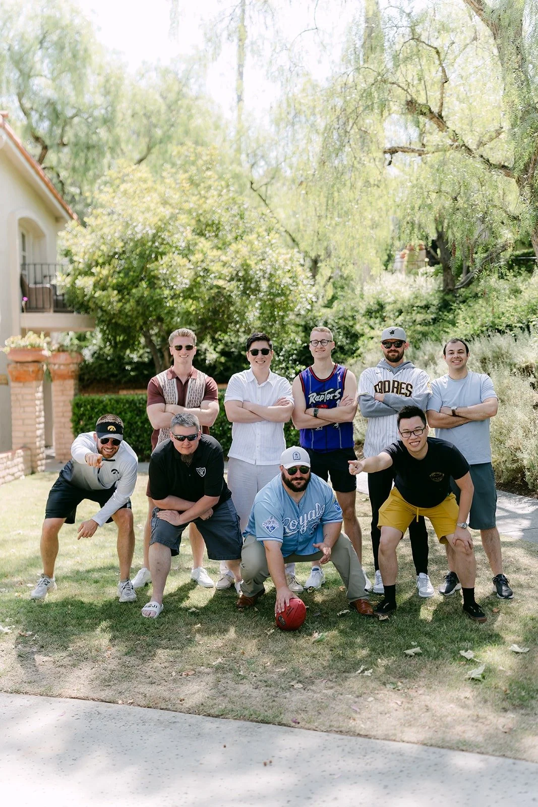 The groomsmen in a football team photo pose on the lawn at Rancho Bernardo Inn