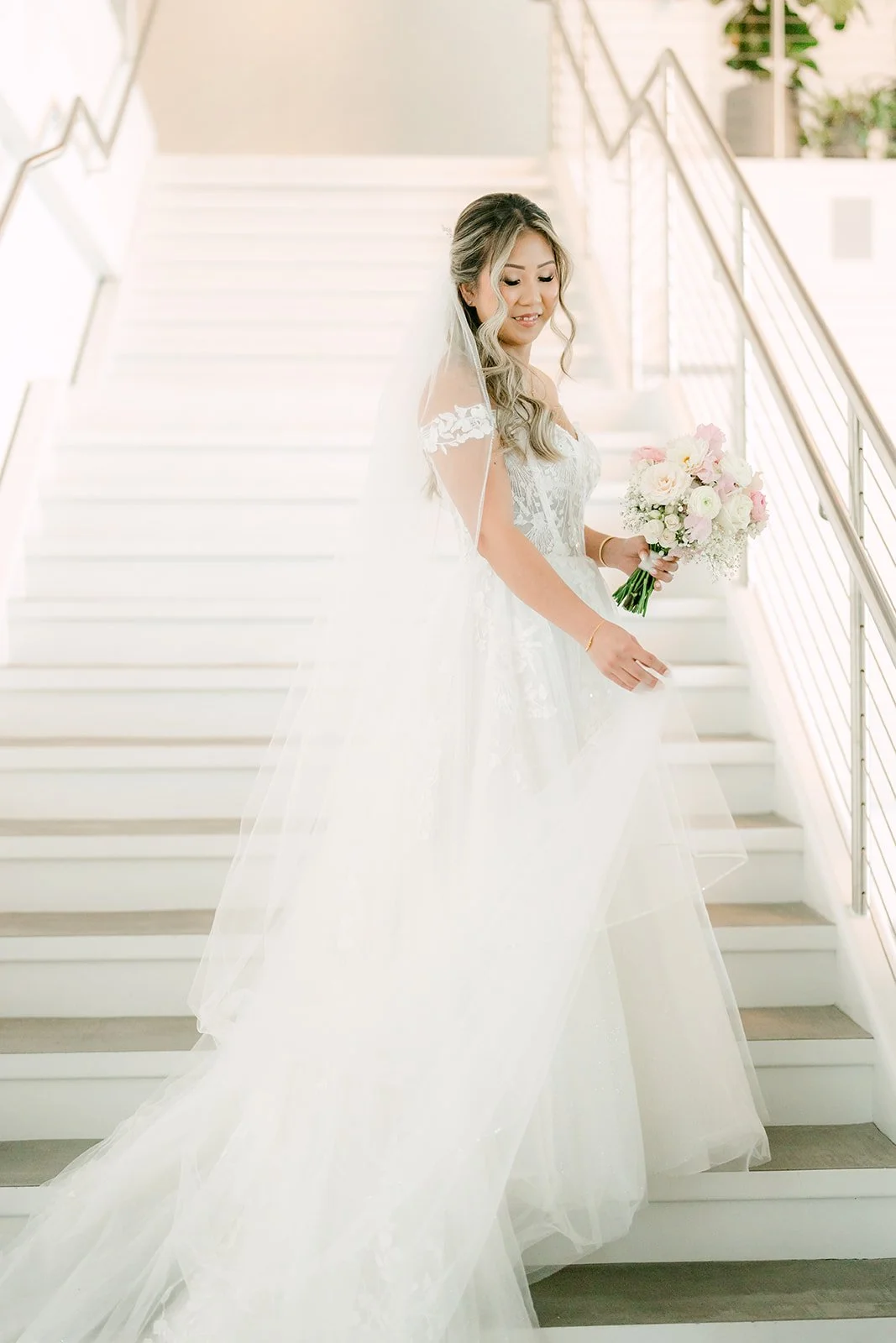Bride on the white staircase at The Modern Long Beach with her veil trailing