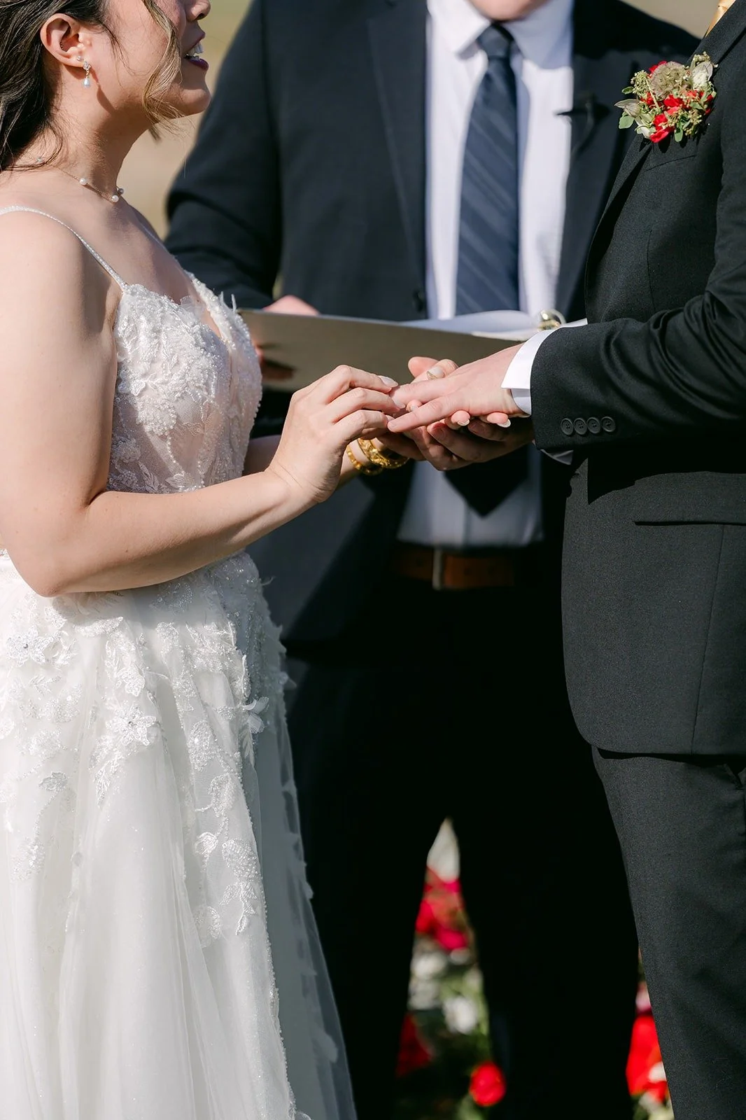 Zach sliding the wedding ring onto Joanne's finger