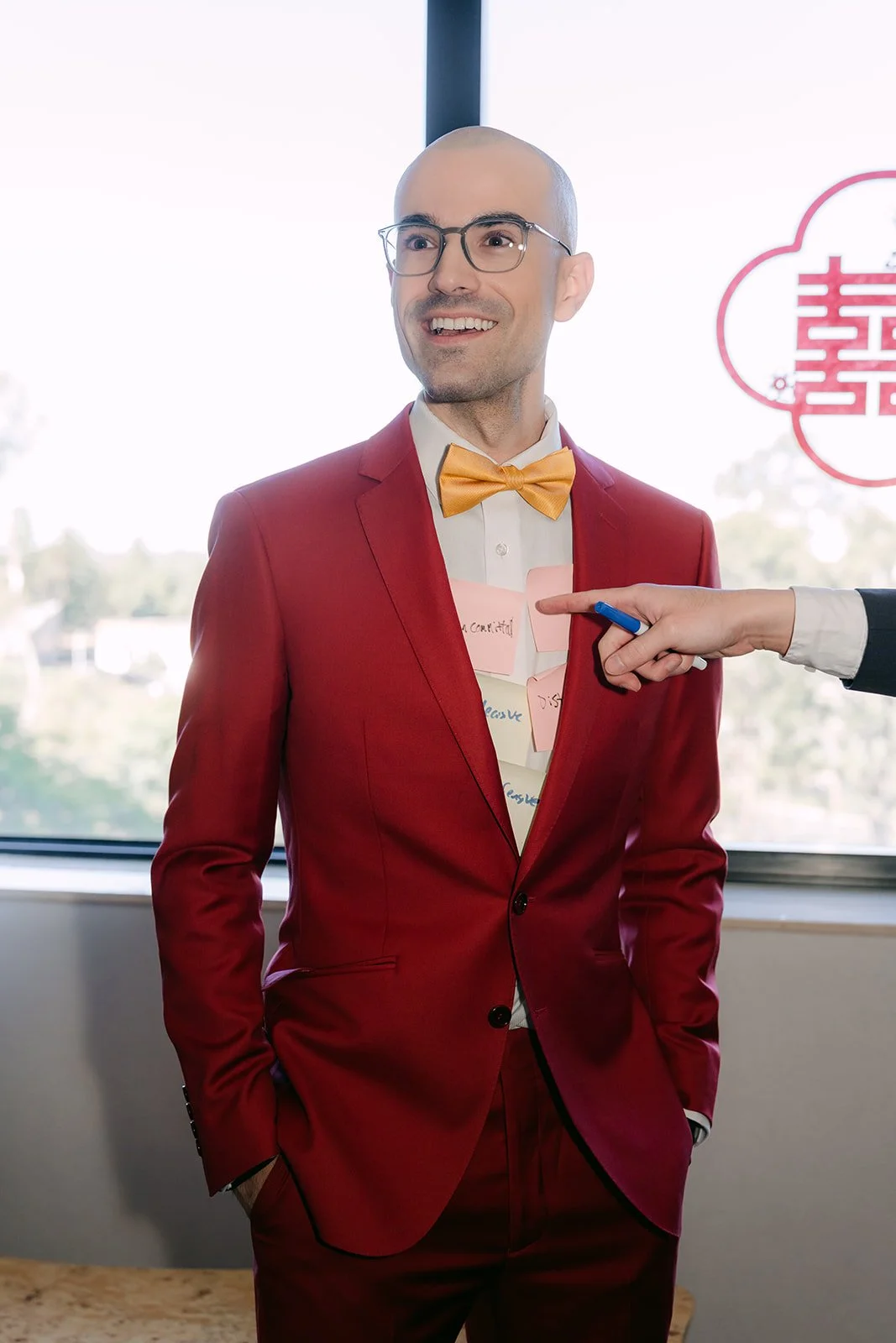 Christian points at his own red suit while the bridesmaids quiz him.