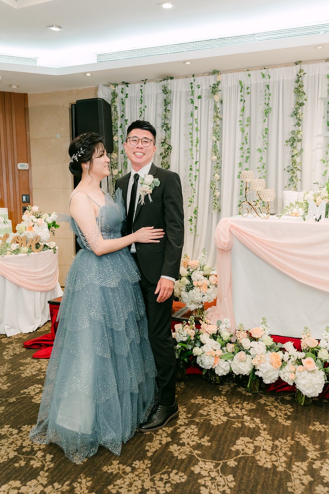 Eunice and Eric together in front of the greenery backdrop, photographed by One and Only Production