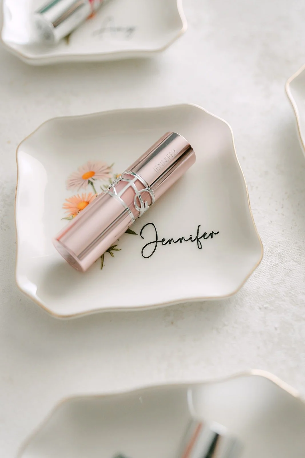 A rose gold lipstick engraved with Jennifer's name on a white tray