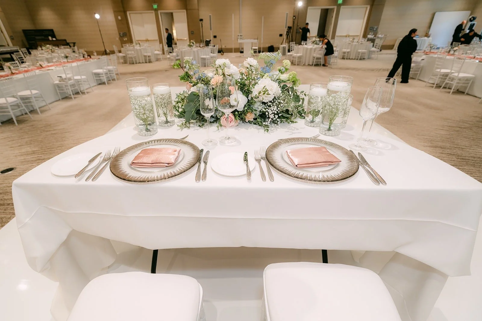 Place settings at the sweetheart table with blush napkins and gold chargers