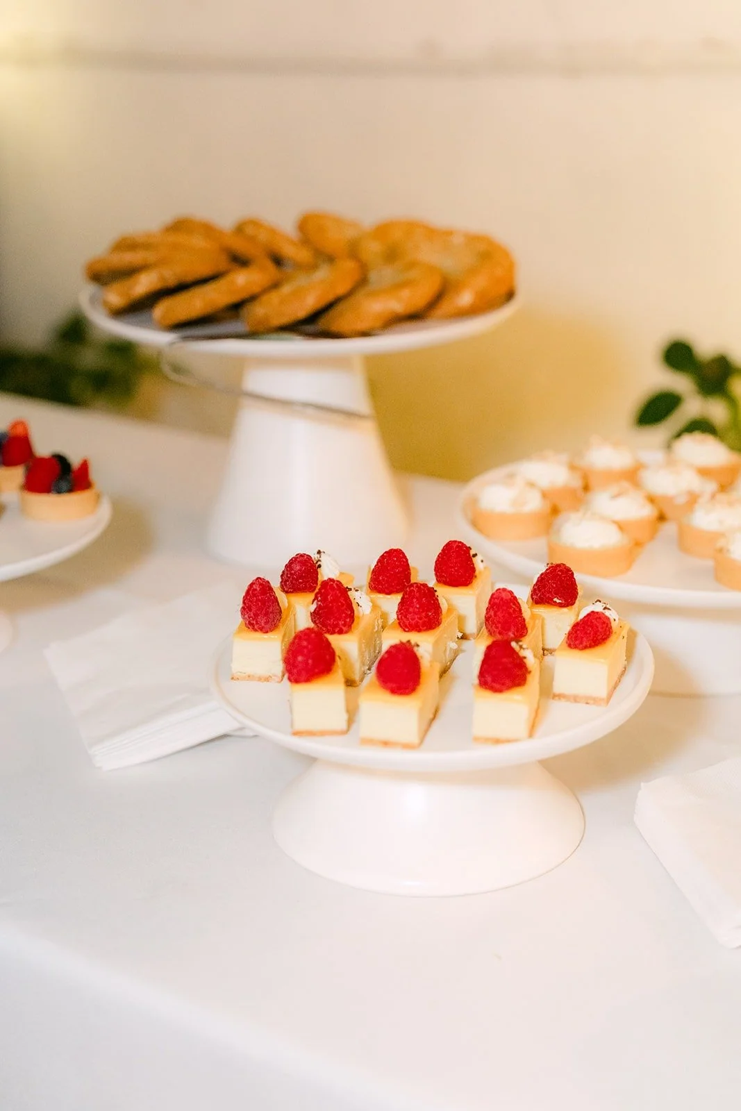 A dessert table with raspberry topped treats and cookies, photographed by One and Only Production