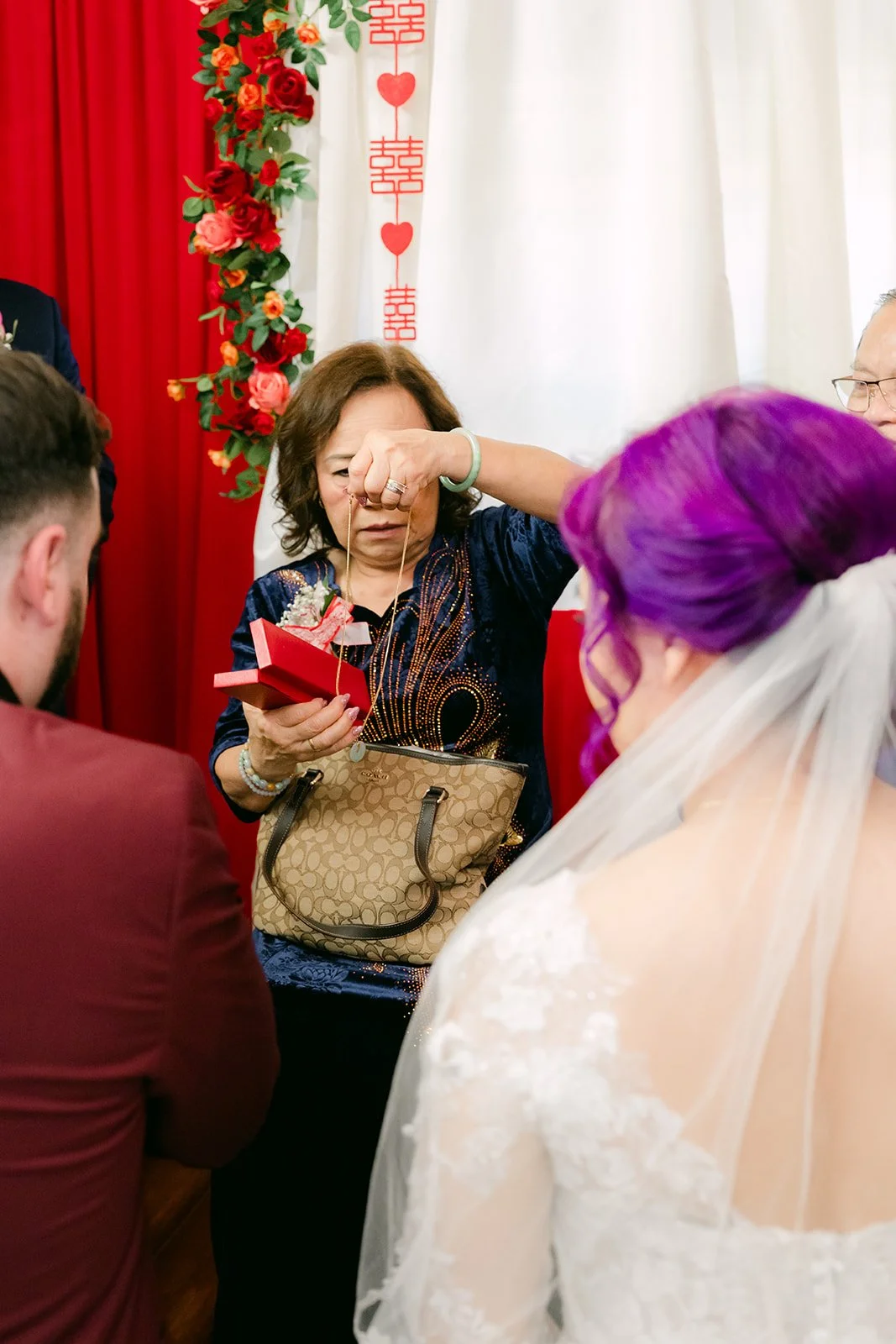 Vanessa serving tea to an aunt, her purple hair and veil in view.
