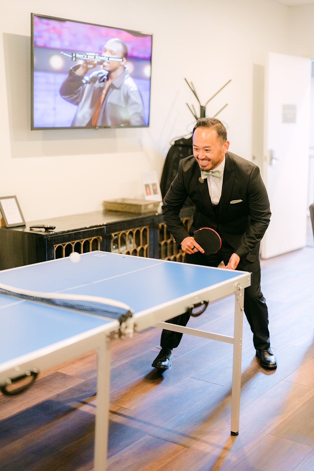 A groomsman playing ping pong while getting ready