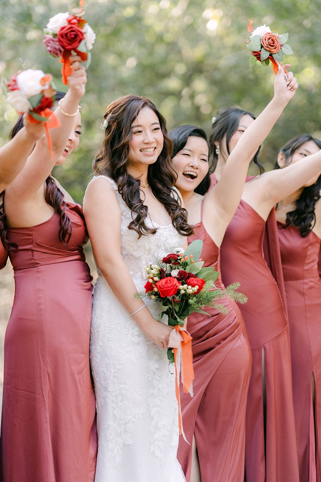 Bridesmaids cheer with their bouquets raised around Shayna
