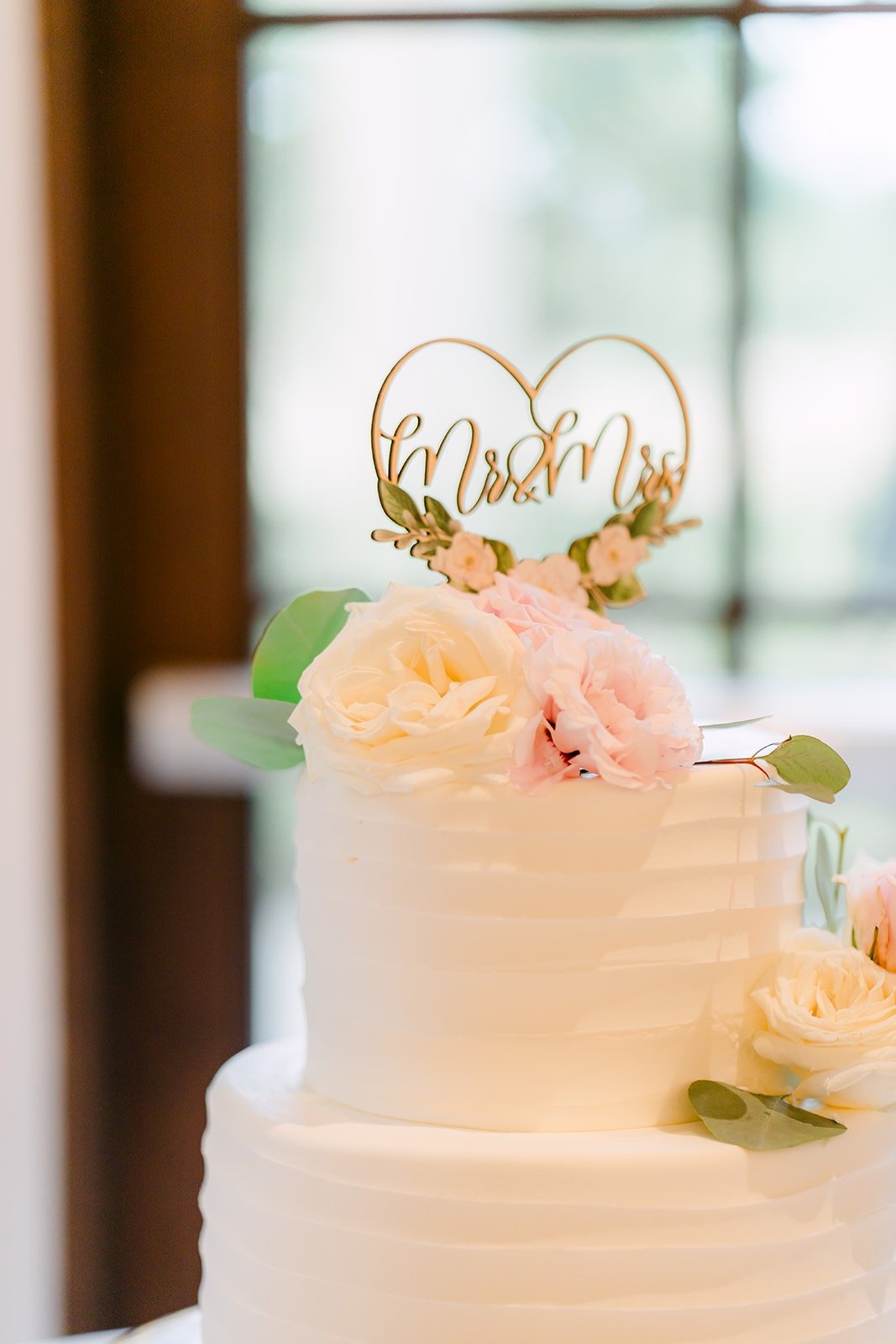 Gold heart cake topper on the white wedding cake