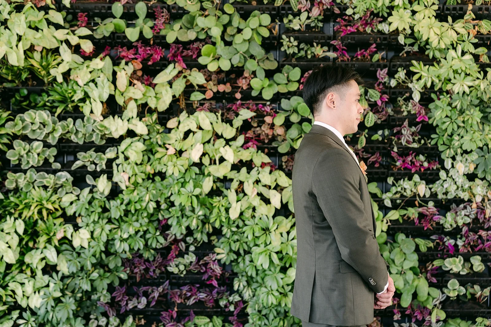 Alex waiting at the living wall at The Colony House before the first look