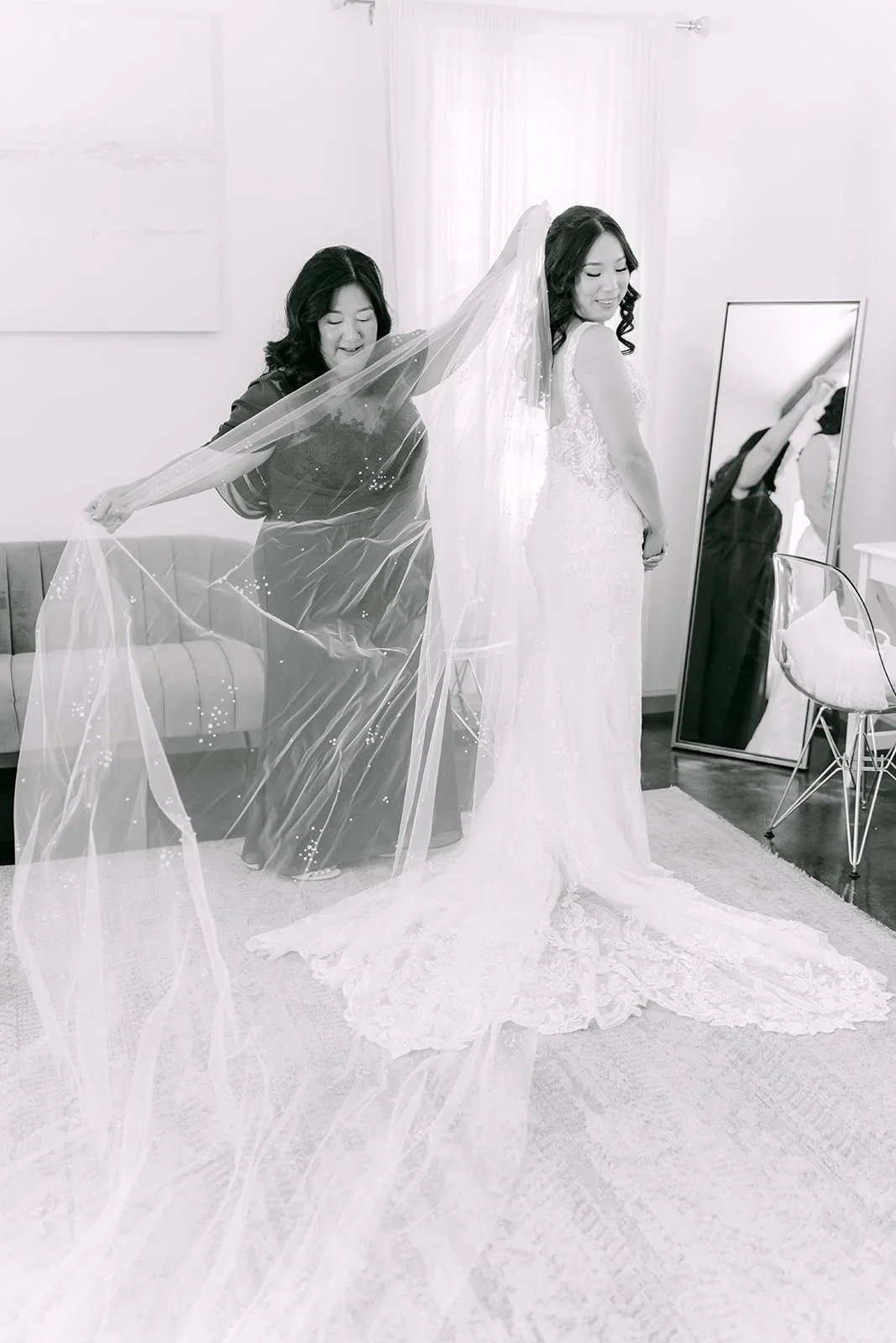 Kelli arranging her long veil in a black and white frame, photographed by One and Only Production